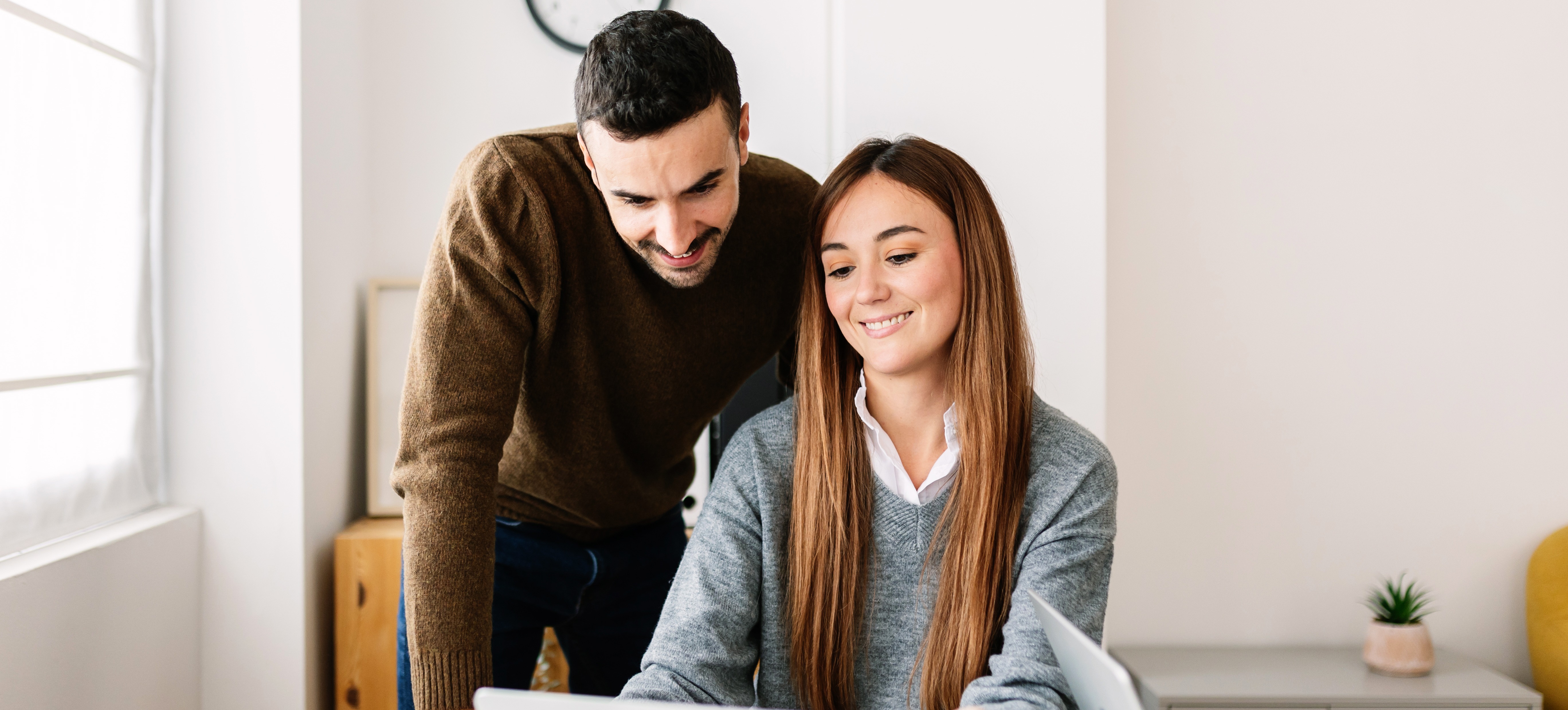 [Featured Image] Two data science colleagues look at a laptop and discuss the relevance of star schema. 
