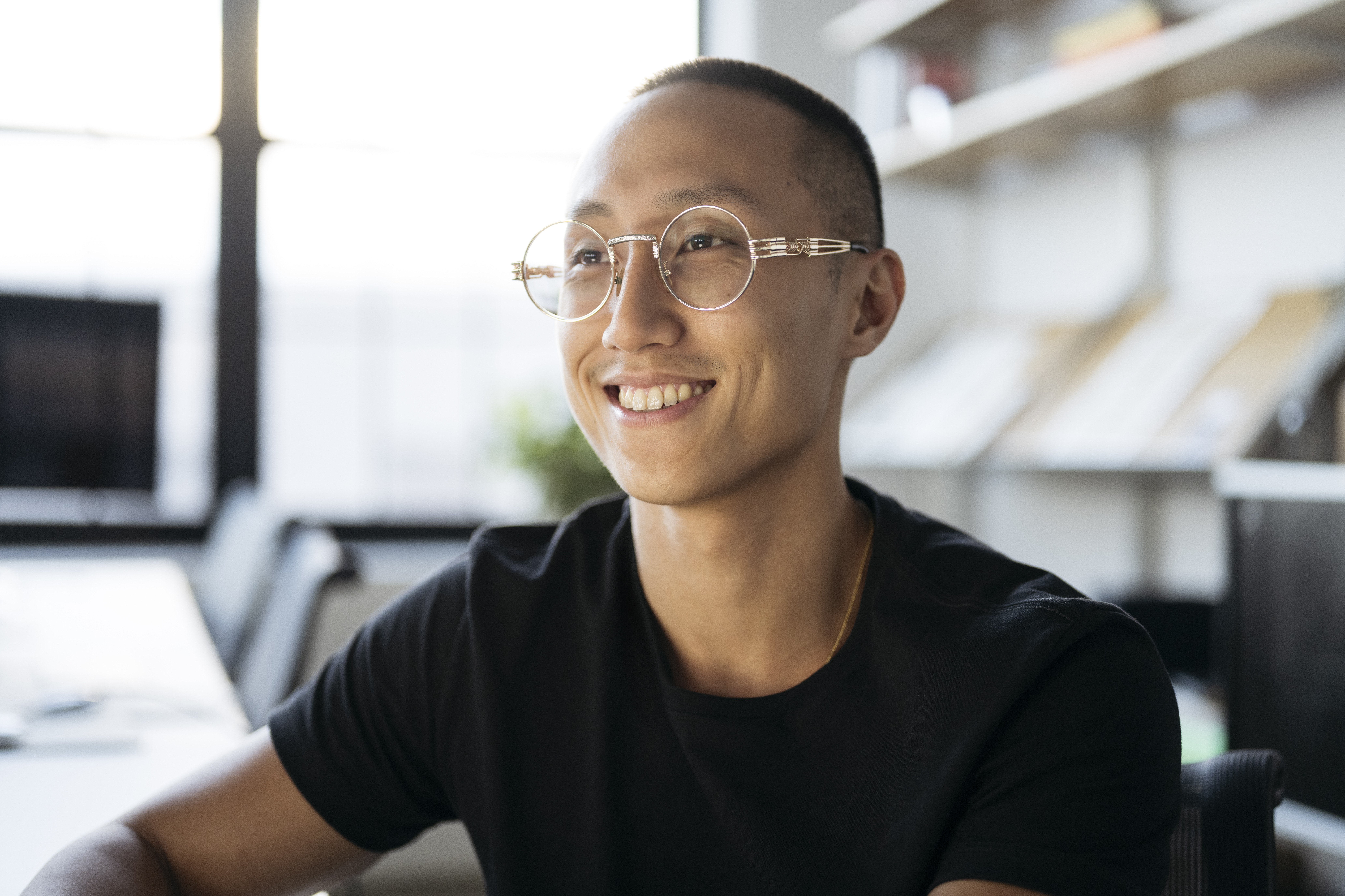 [Featured image] A smiling machine learning engineer sits at his workstation.