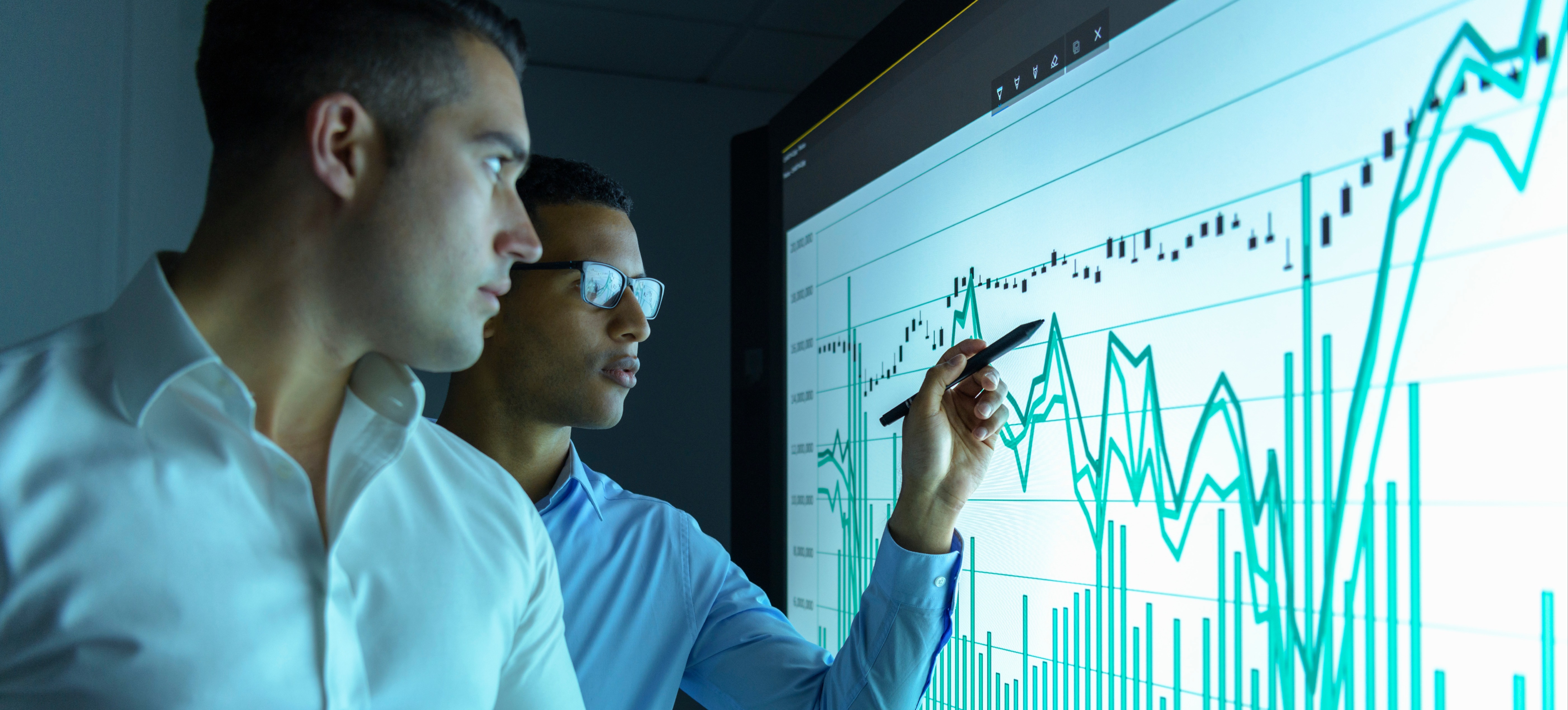 [Featured Image]: Two business intelligence professionals review company data and look for trends to inform decisions.
