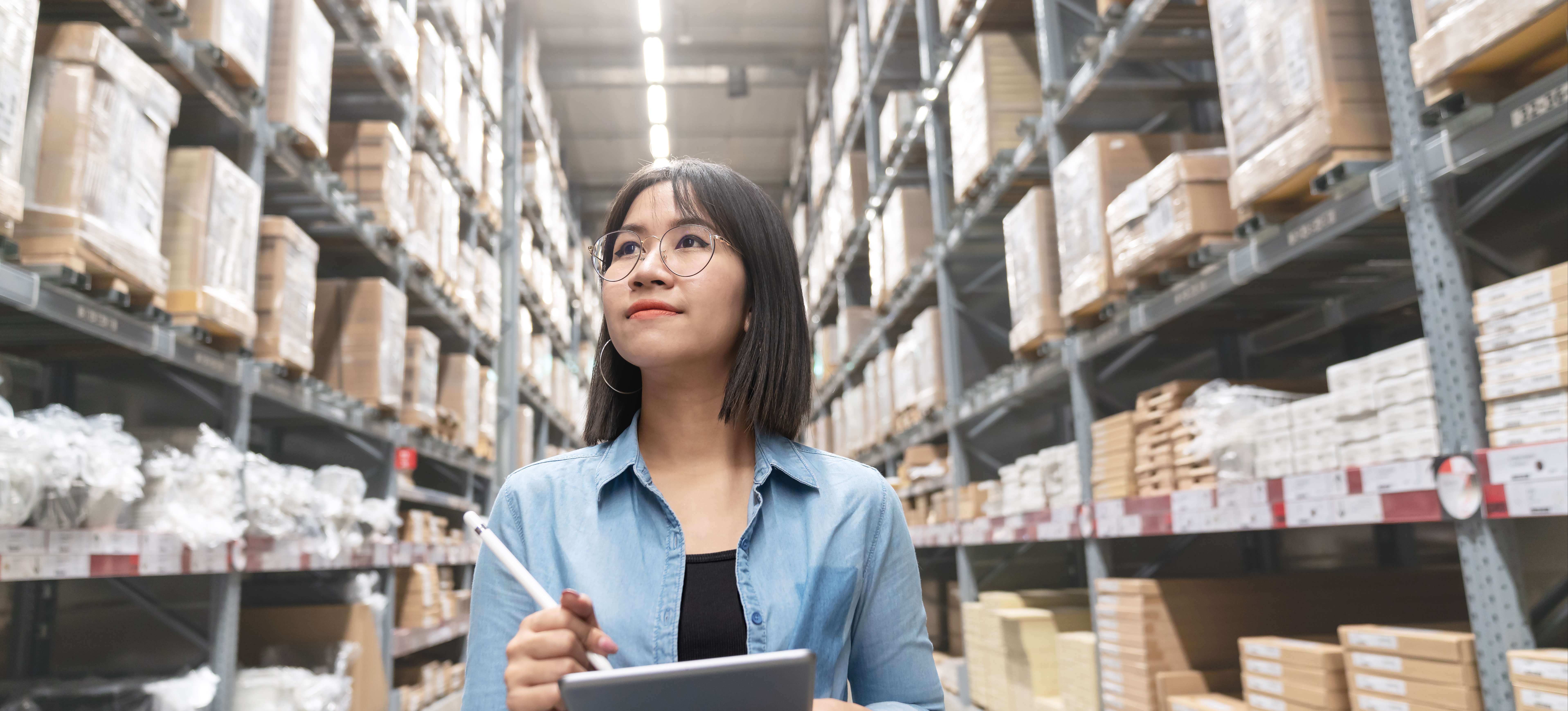 [Featured Image] A retail manager holding a tablet in a warehouse implements a new inventory management system as part of a business process improvement plan.
