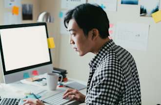 [Featured image] Man at desk reviewing data on computers