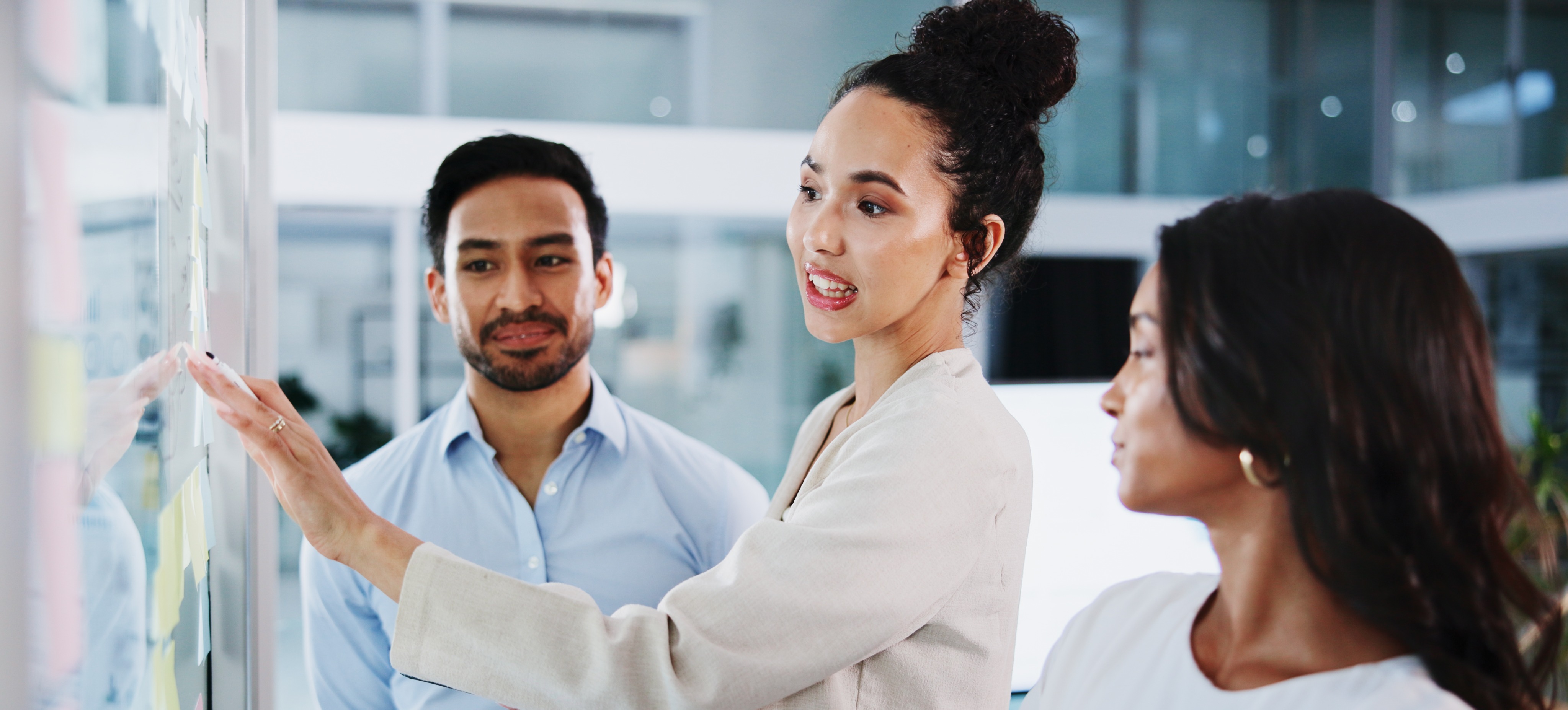 [Featured Image] A team of C-level professionals stands together and uses strategic roadmapping to visualize their company's goals and vision. 
