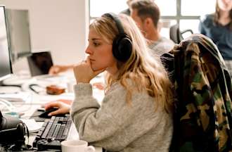 [Featured Images] A woman works at a desktop computer in an office.