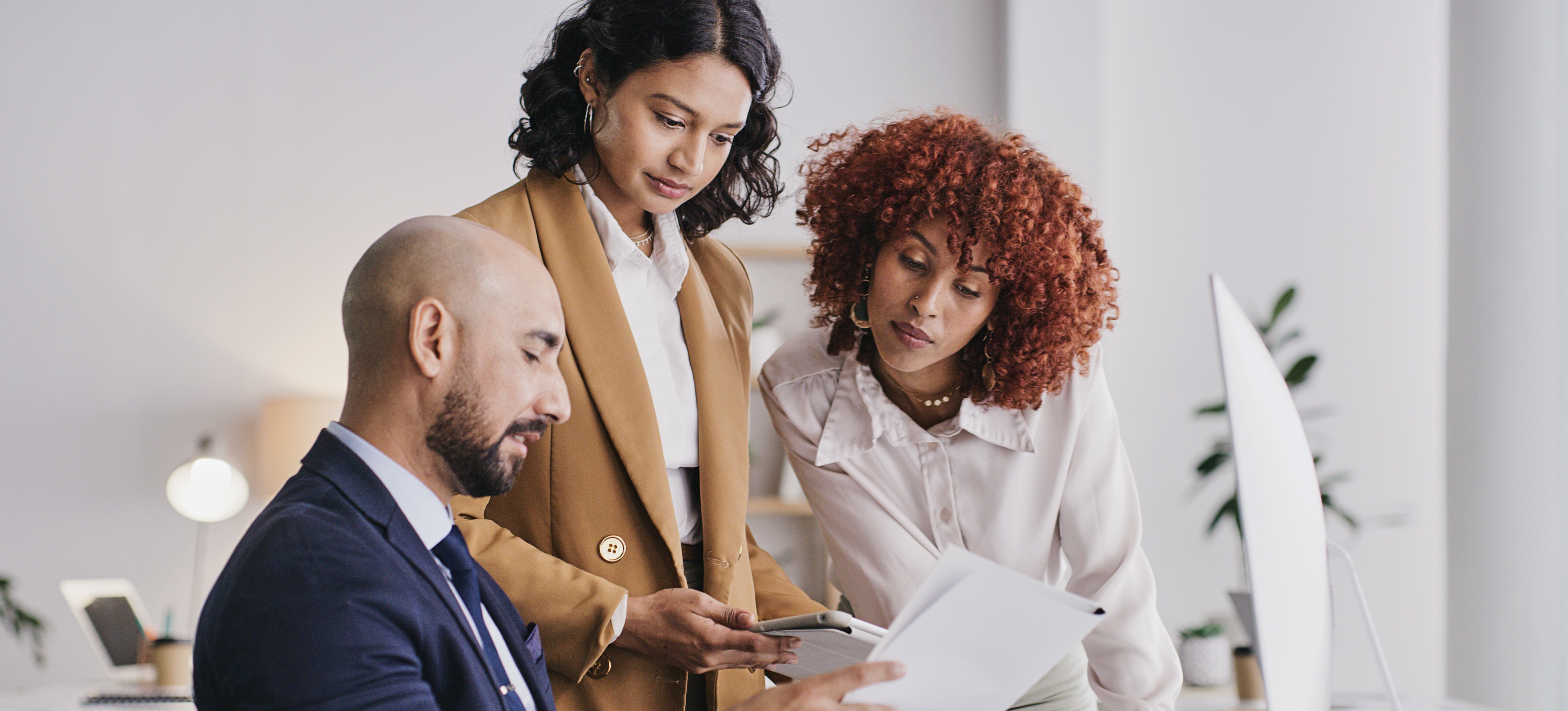 [Feature Image] A big data analyst discusses the details of a report for an impending presentation to company stakeholders with two colleagues.
