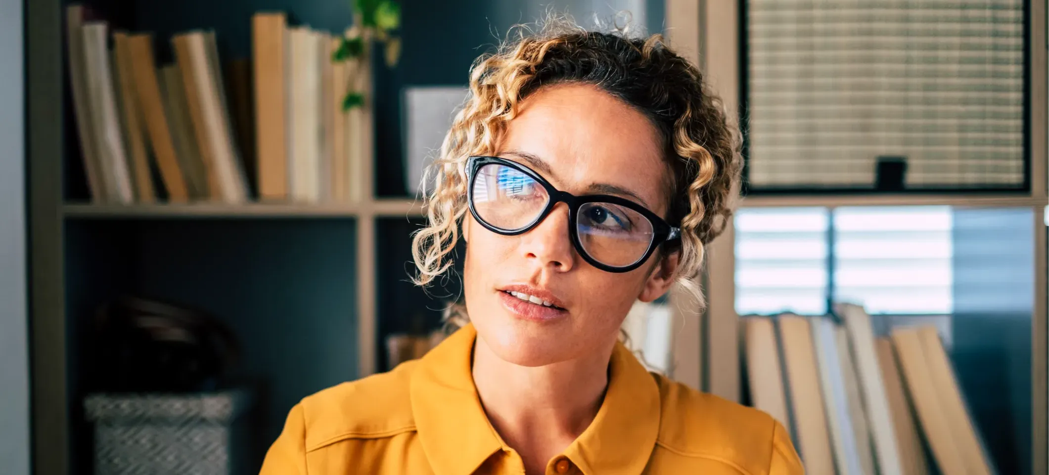 [Featured Image] A professional wearing glasses and a pensive expression thinks about what they are learning as part of the AI boot camp they are taking. 
