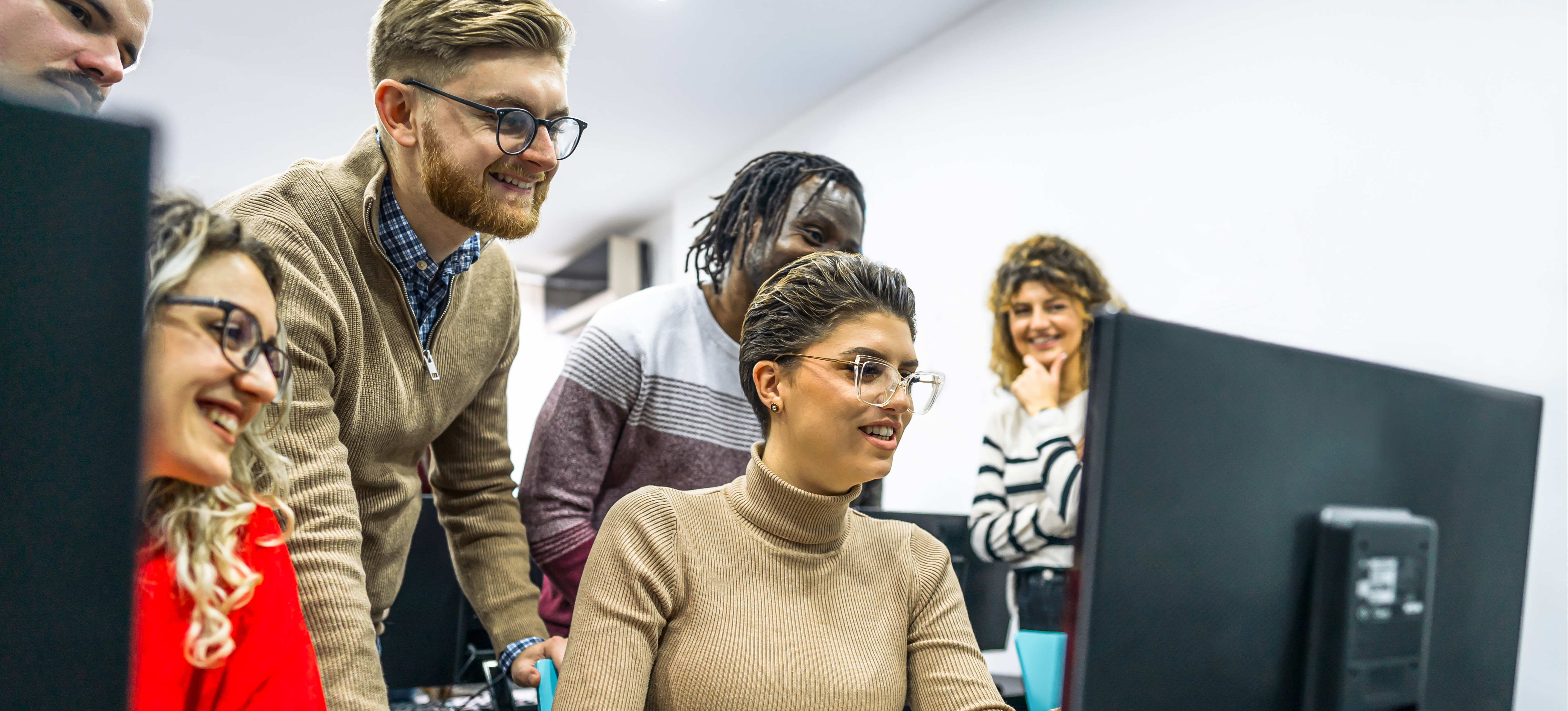 [Featured Image] Students on a front-end developer career path gather around an instructor to learn how to design and create a website.
