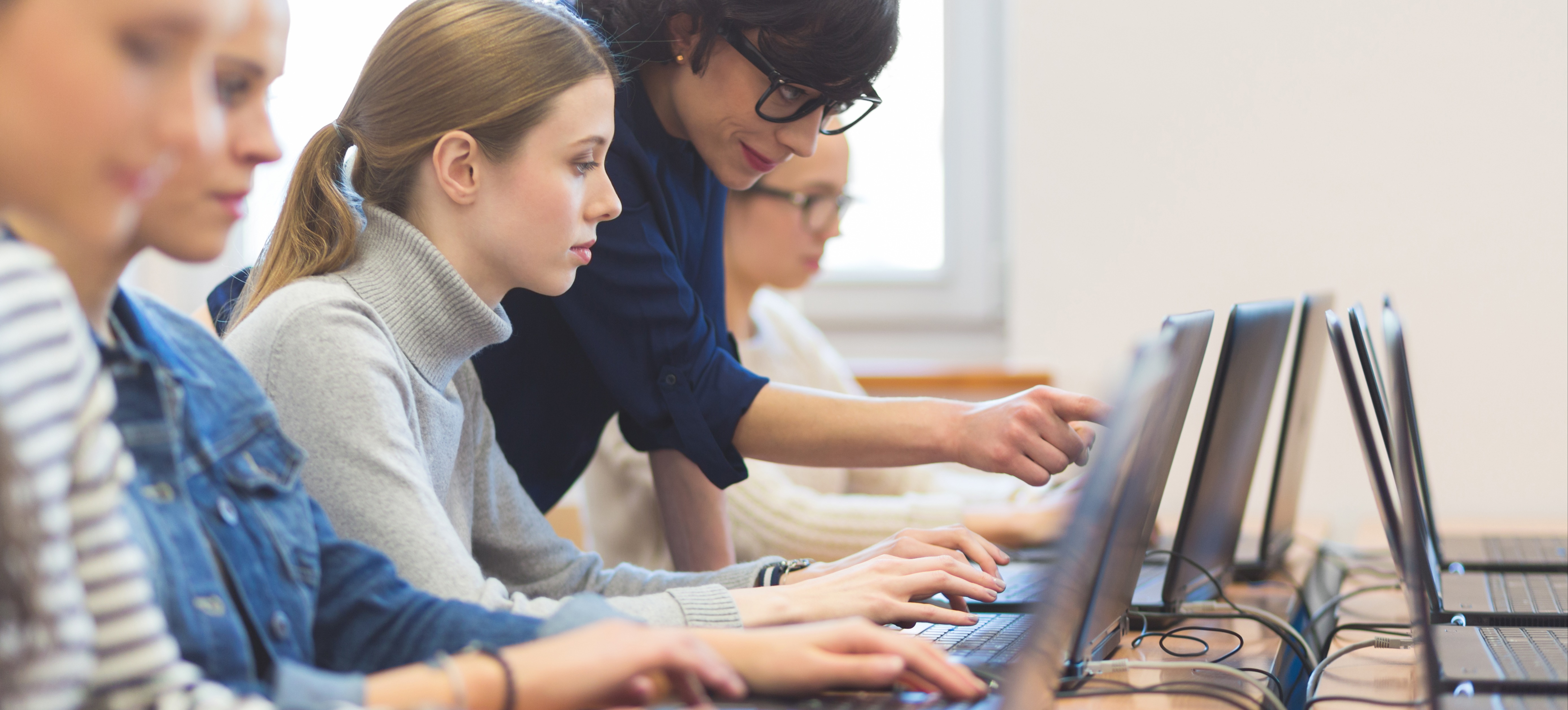 [Feature Image] Learners work on laptops in an instructor-led UI design certification training program. 
