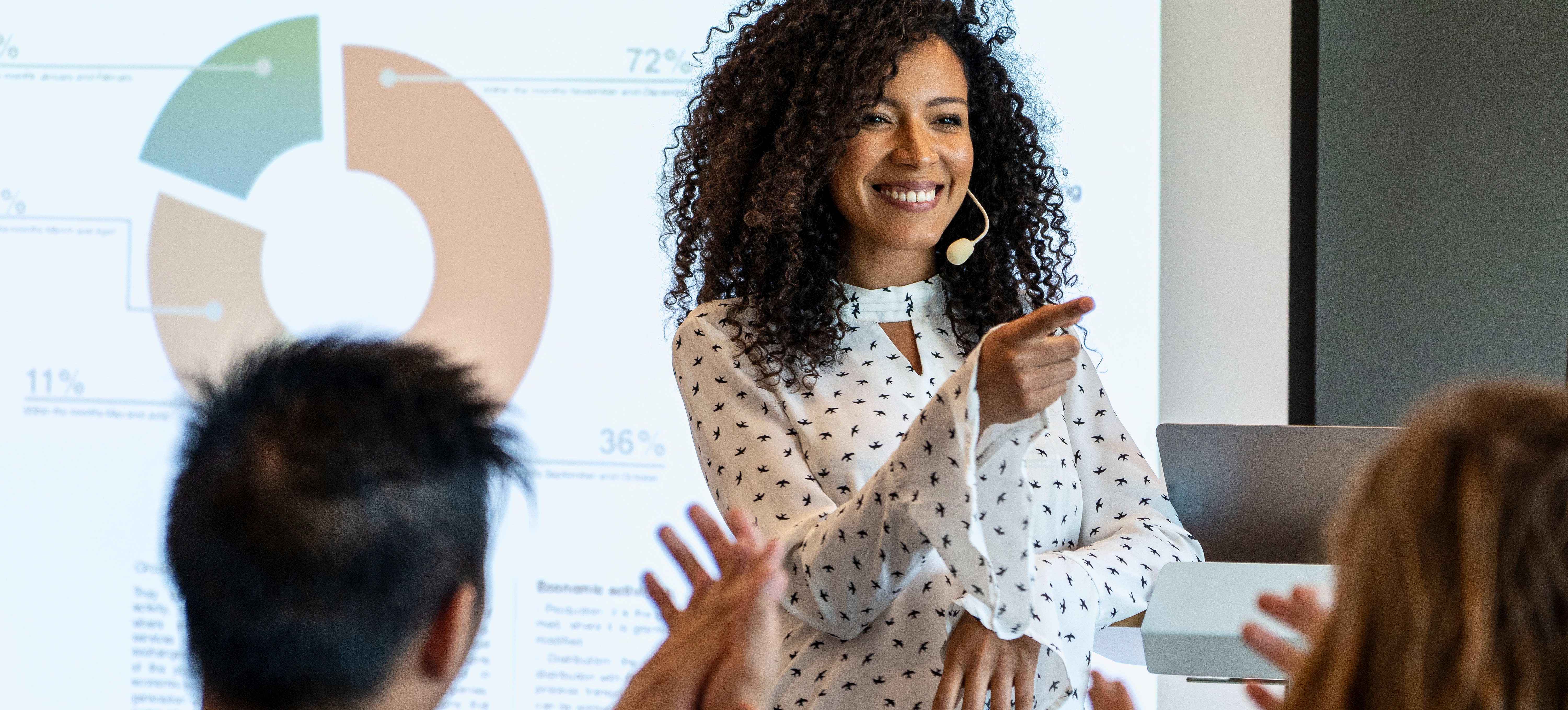[Featured Image] A people manager conducting a training session in a workplace setting, engaging with colleagues while presenting key insights.
