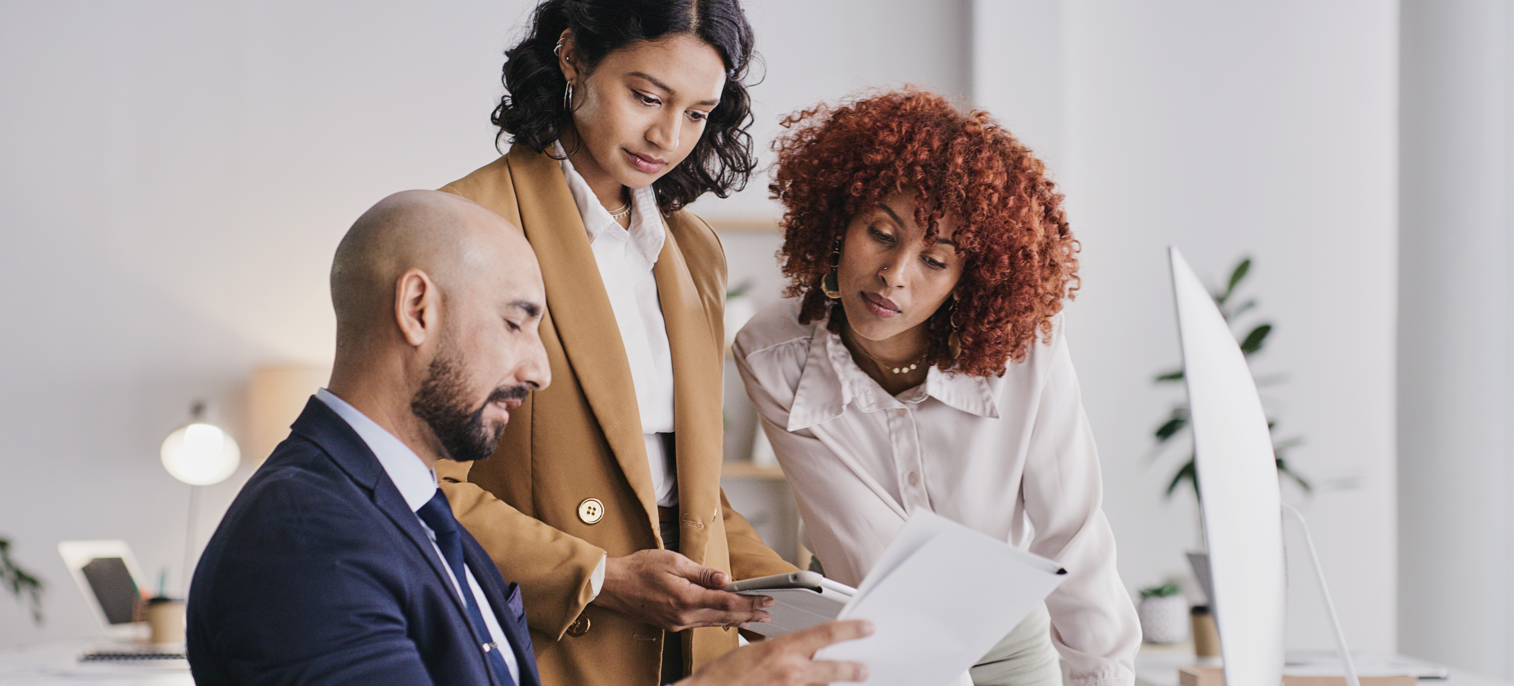 [Feature Image] An accounting clerk consults with other business professionals as they complete complex bookkeeping tasks.
