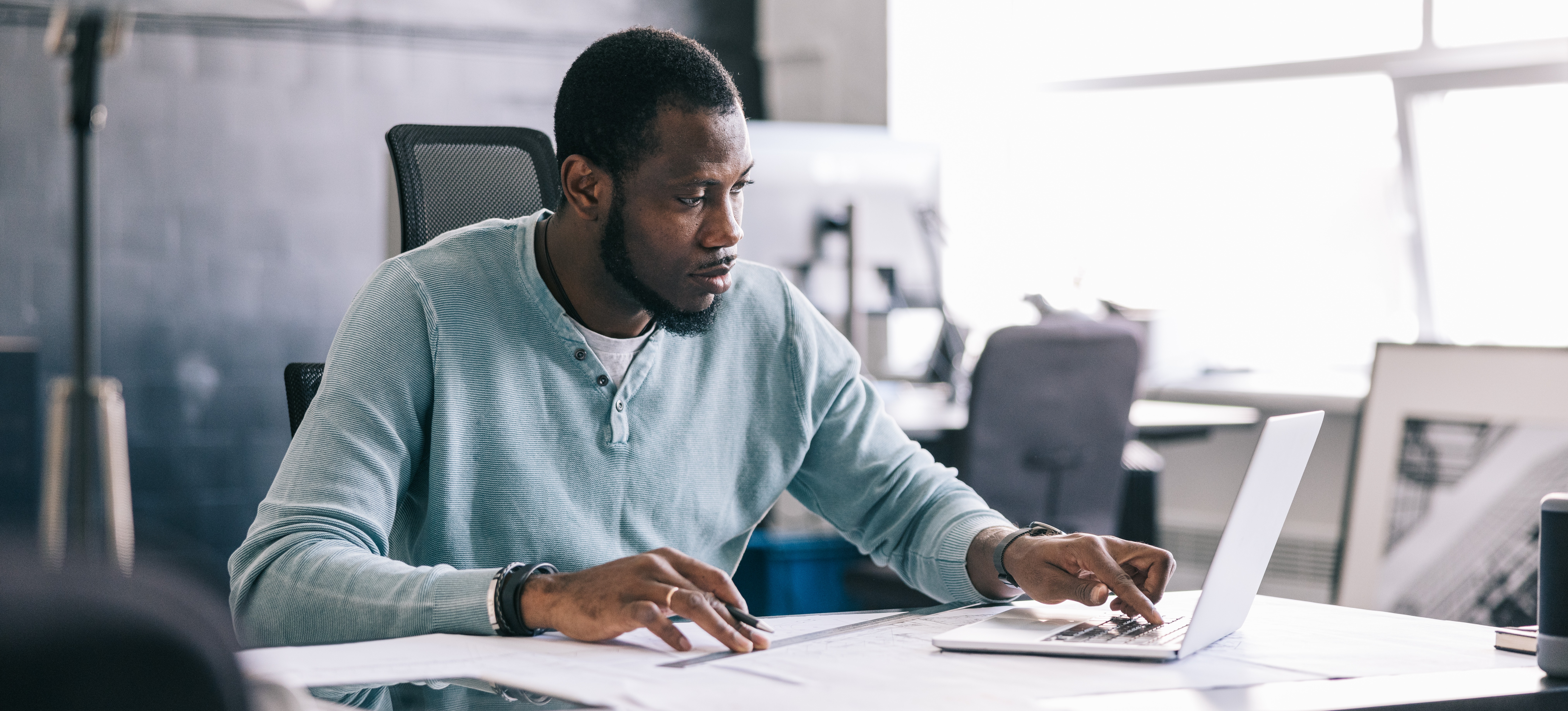 [Featured Image] Sitting at their desk, a professional works through a feasibility study to determine if their new idea is likely to succeed. 
