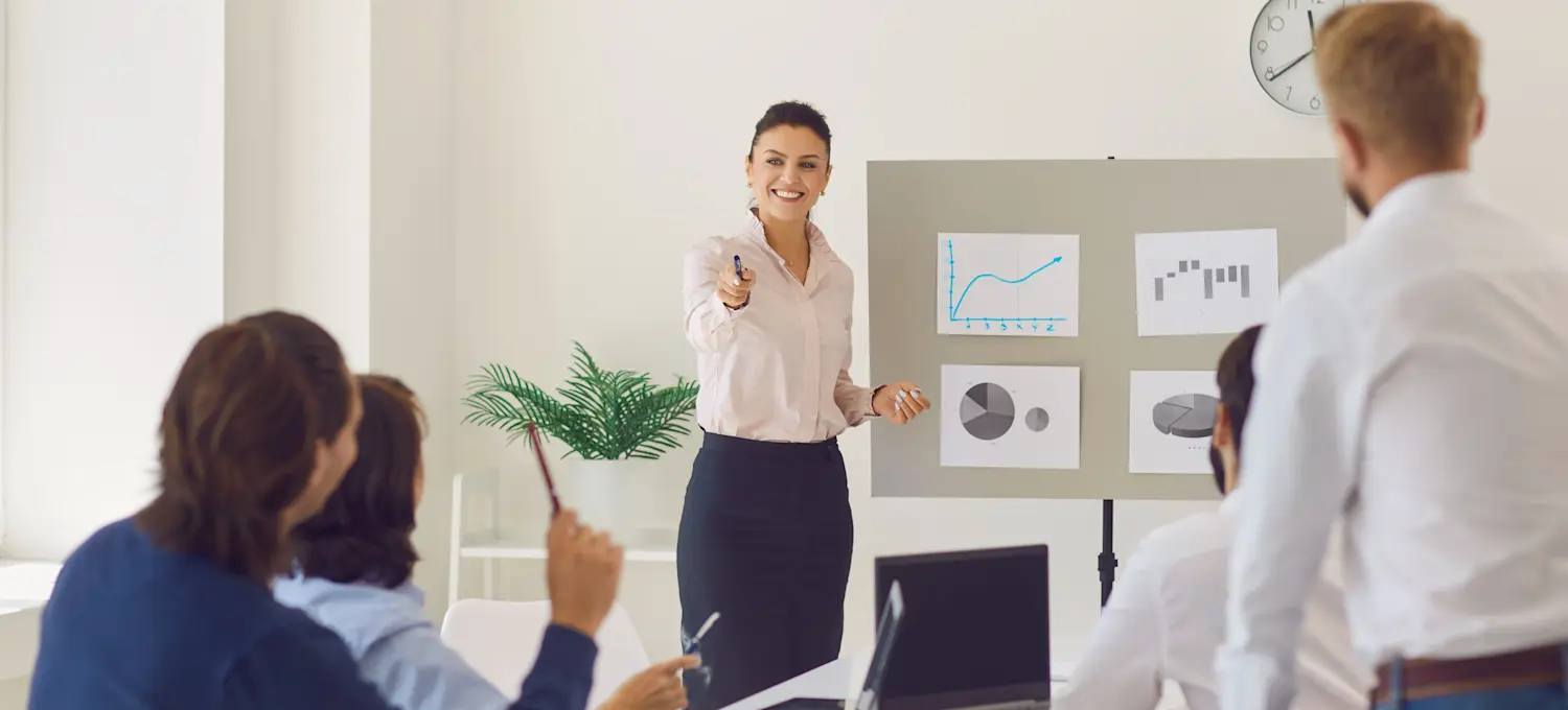 [Featured Image] A person working for a sales operations manager salary talks to the sales team during a business meeting, pointing to a colleague who has their hand raised to make a comment.

