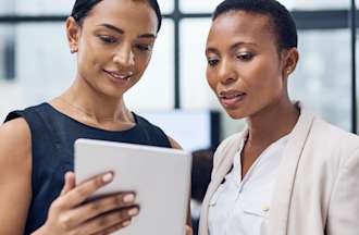 [Featured Image] A chief data officer shows an employee some information on her tablet. 