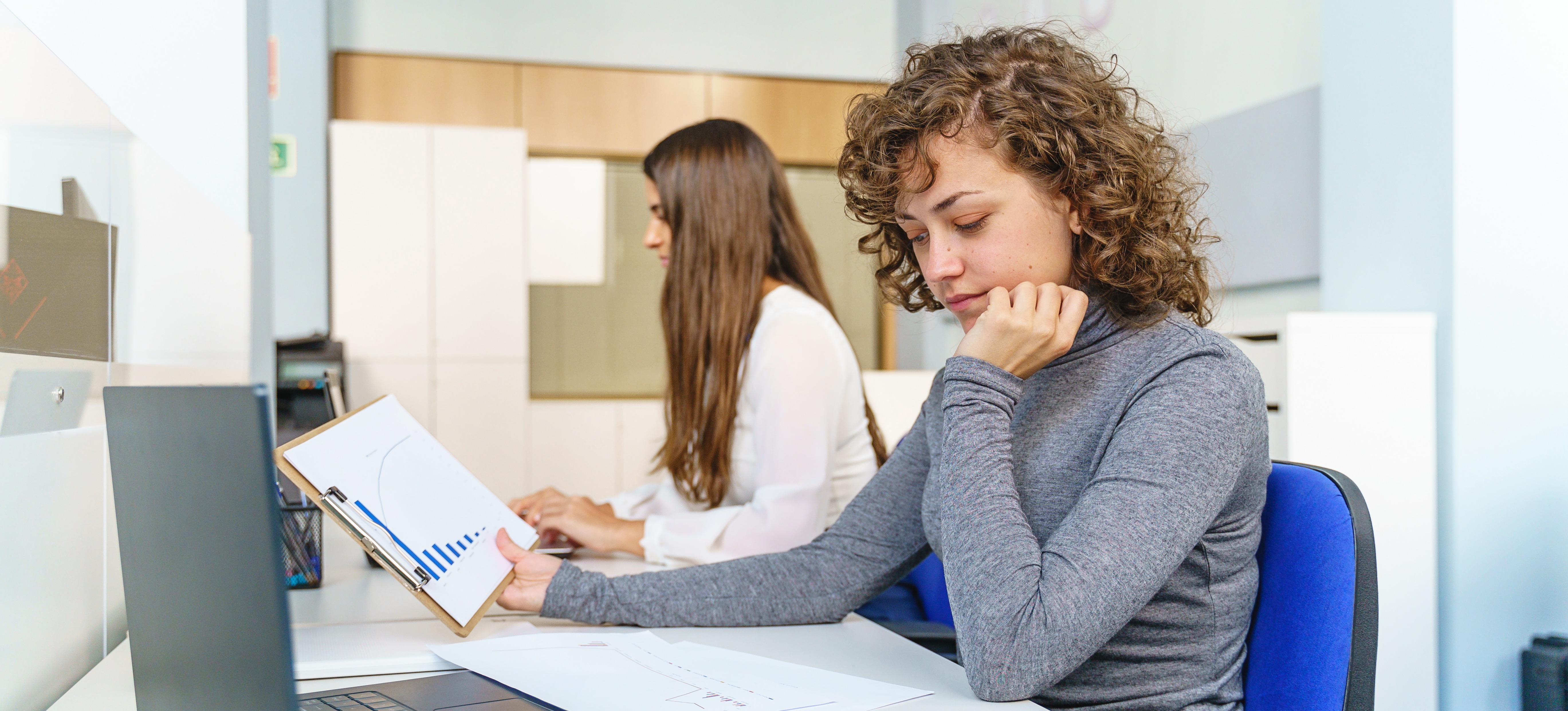 [Featured Image] Colleagues collaborating in a professional setting, analyzing printed graphs and using a computer while discussing random forest versus neural networks in AI and machine learning.
