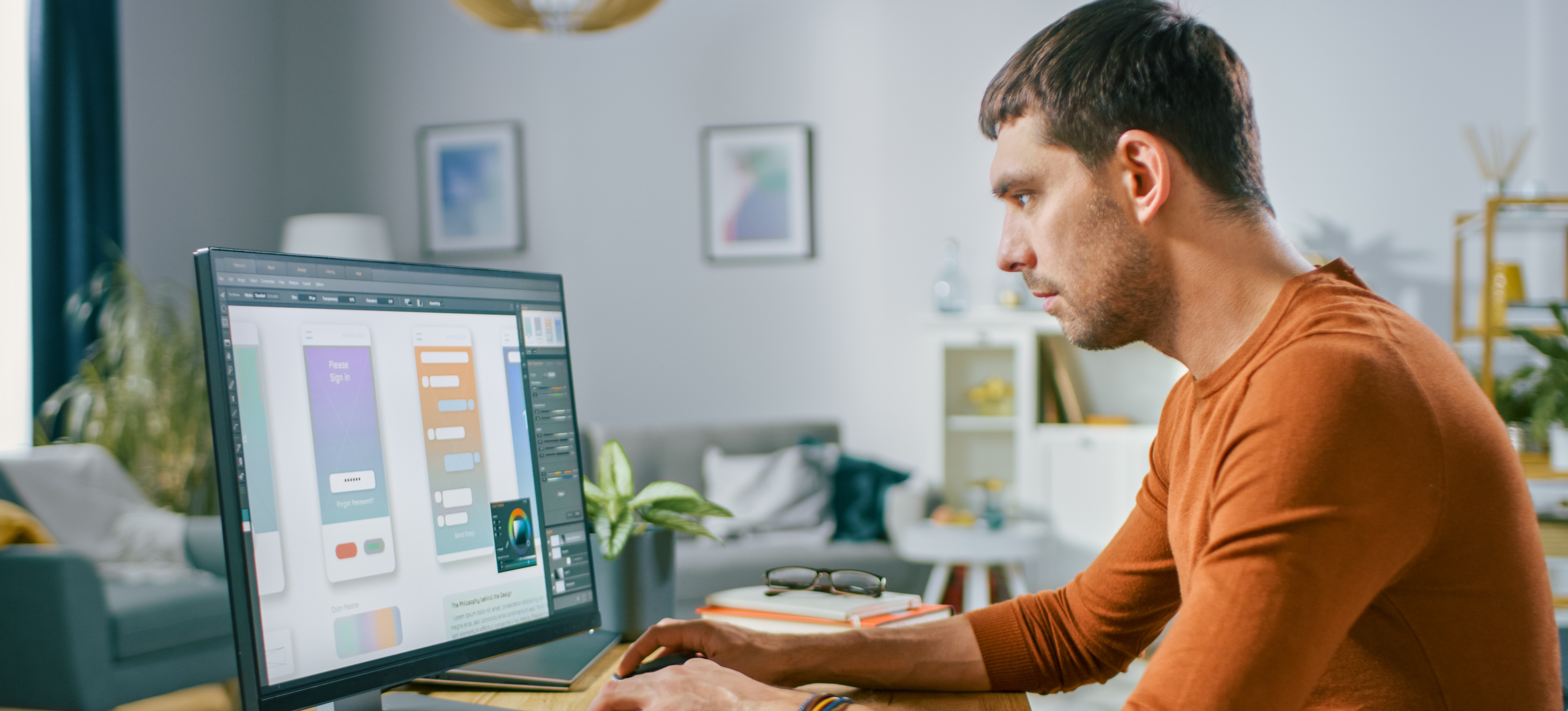 [Image en vedette] Un concepteur UX vêtu d'un T-shirt orange à manches longues travaille sur un prototype sur son ordinateur de bureau. 