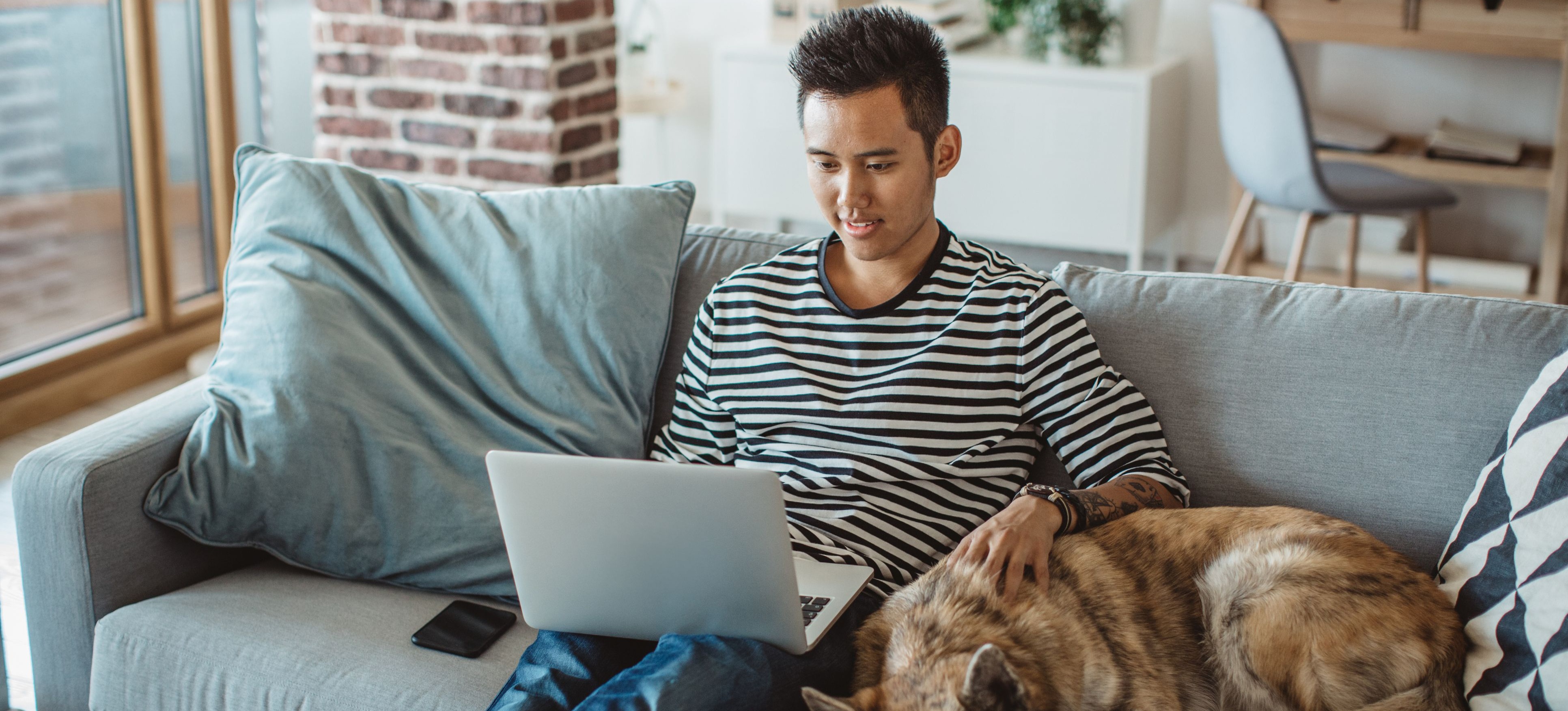 [Hauptbild] Ein IT-Support-Spezialist lernt etwas über DHCP, während er mit seinem Hund auf der Couch sitzt.