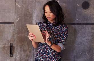 [Featured image] A person in a polka-dot shirt stands in front of a wood-paneled wall and taps the screen of their tablet.