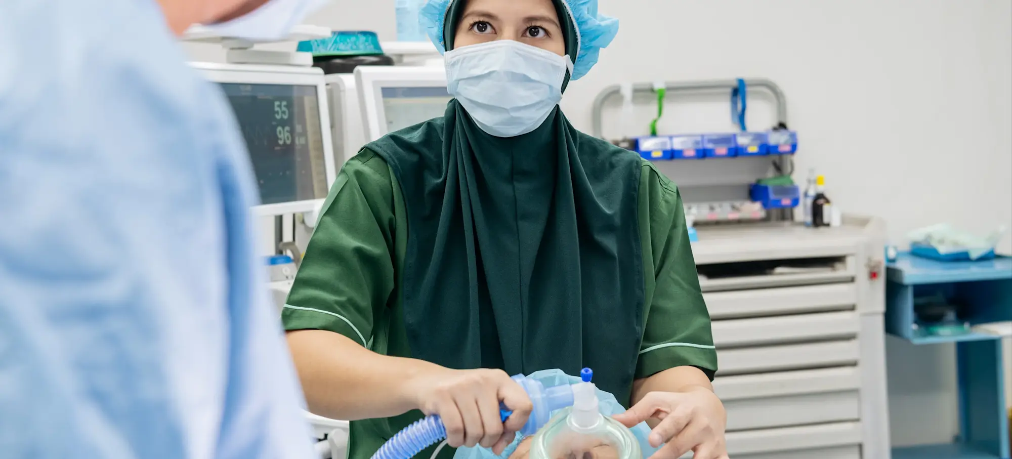 [Featured Image] A nurse anesthetist cares for a patient in an operating room.