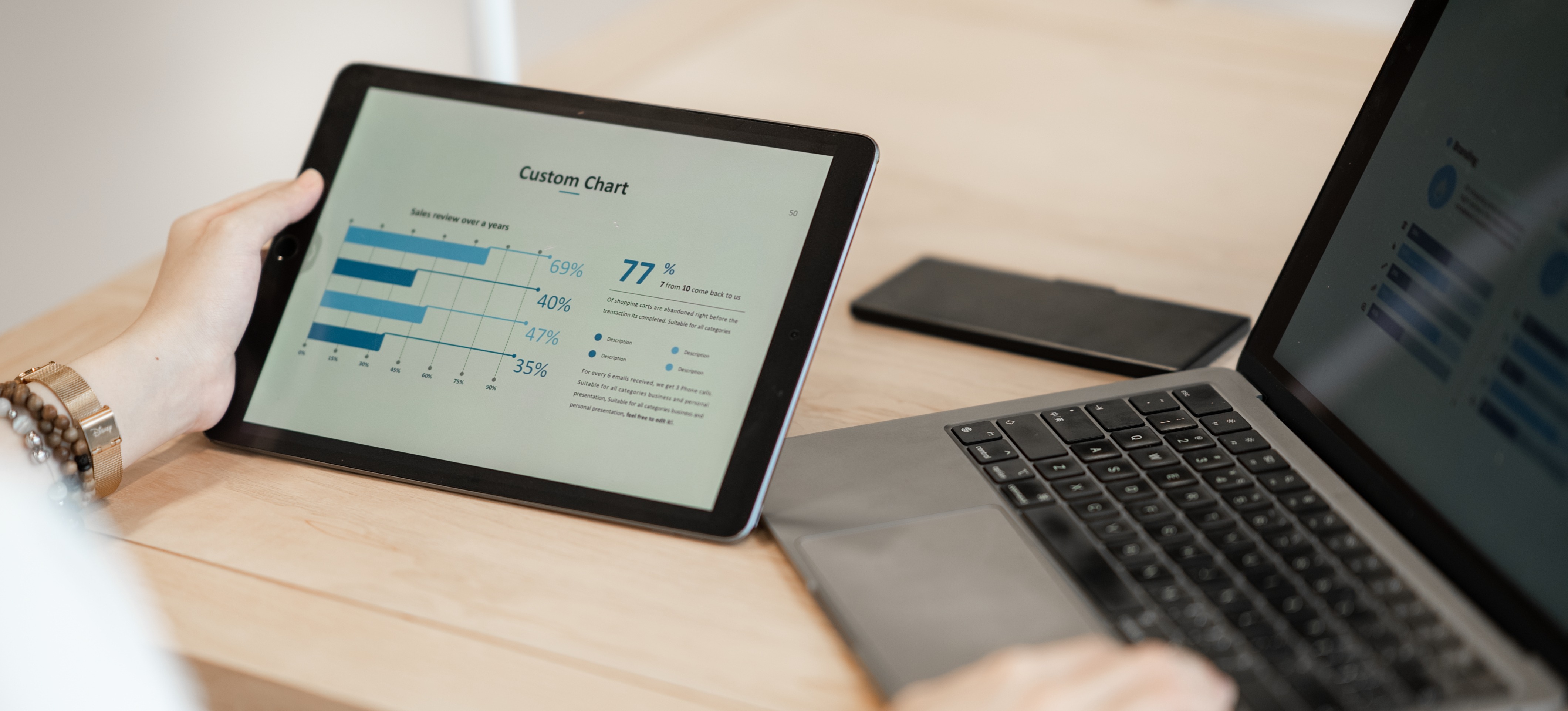 [Featured Image] A businesswoman's hand is holding a tablet with a chart created using business analytics software.