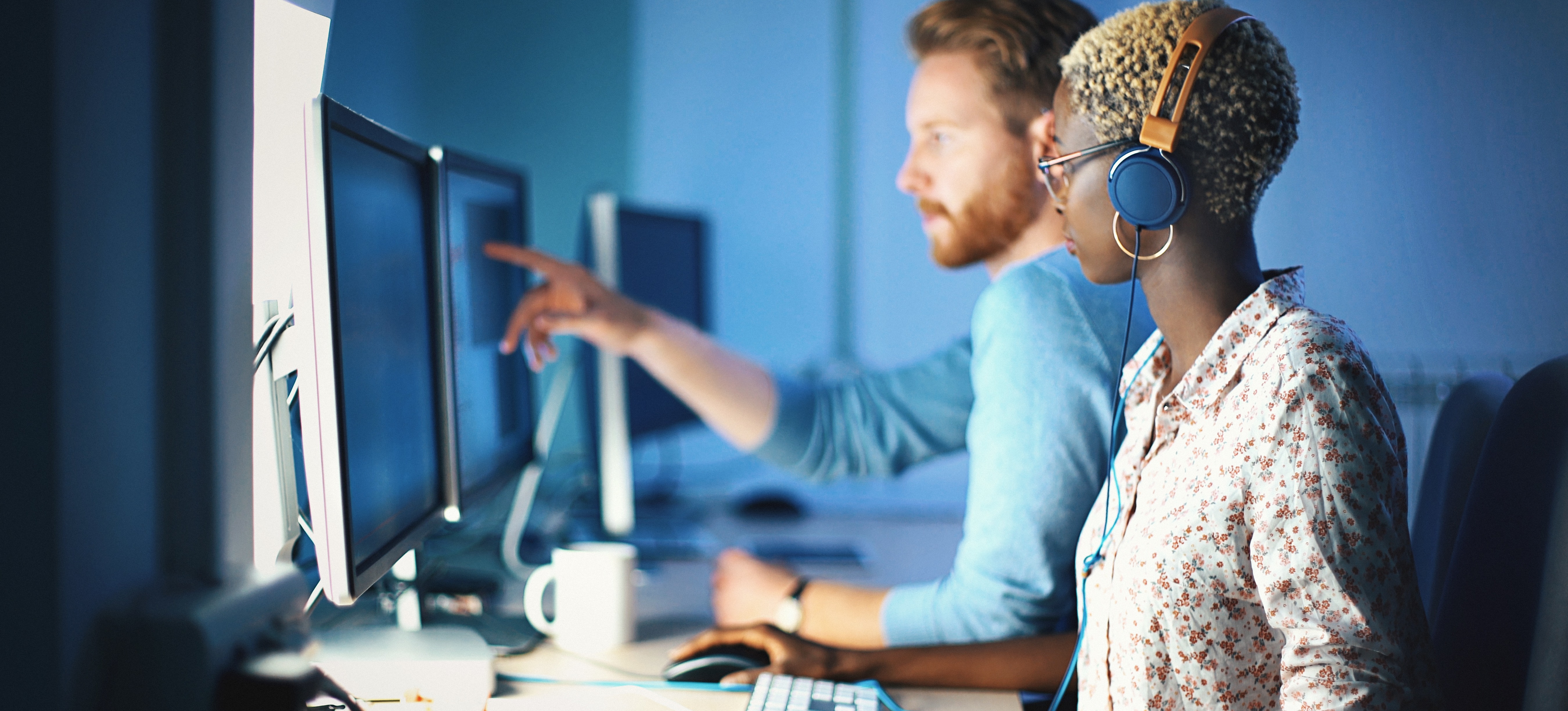 [Featured Image] Two programmers use JavaScript data visualization libraries as they work on computers.
