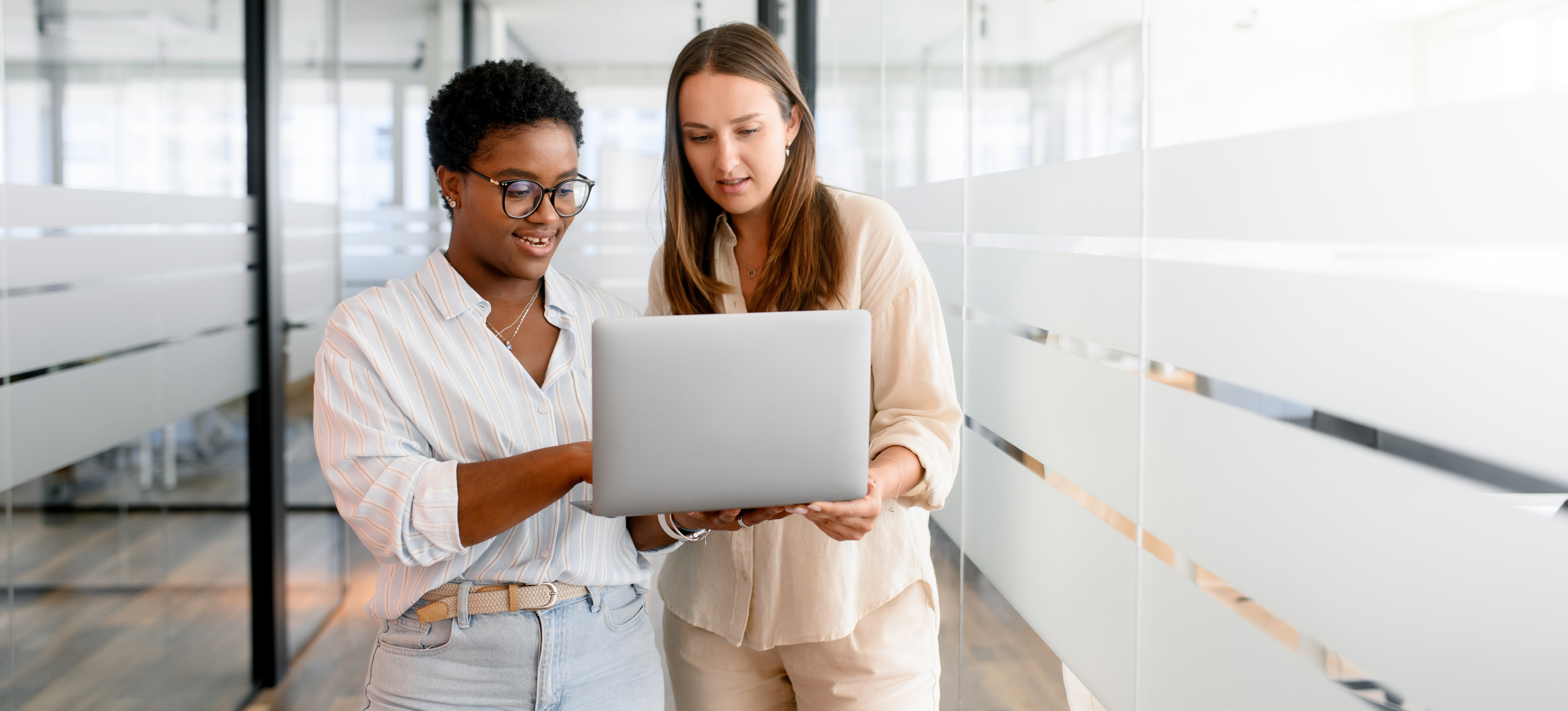 [Featured Image] Two coworkers review an analysis of variance (ANOVA) on a laptop while discussing their findings. 