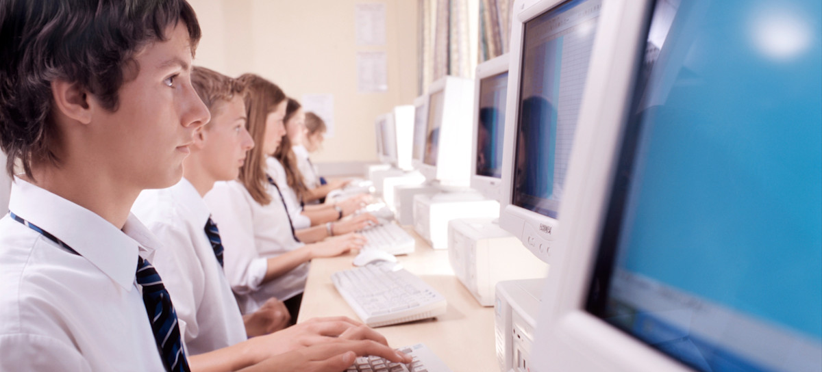 [Featured Image] A row of high school students using computers in school are using the overlearning technique to learn.