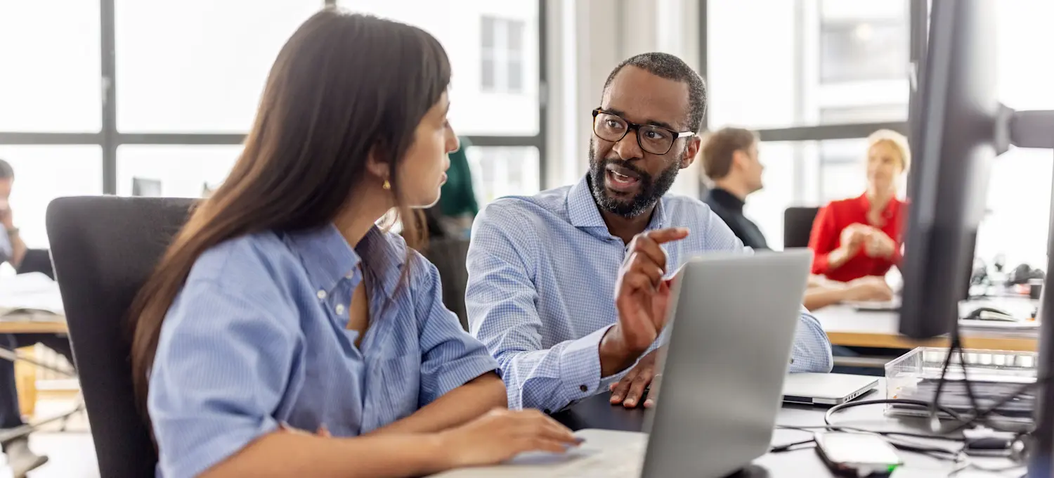 [Featured Image] A professional teaching another person about the concepts of dynamic typing vs. static typing in a collaborative workspace.
