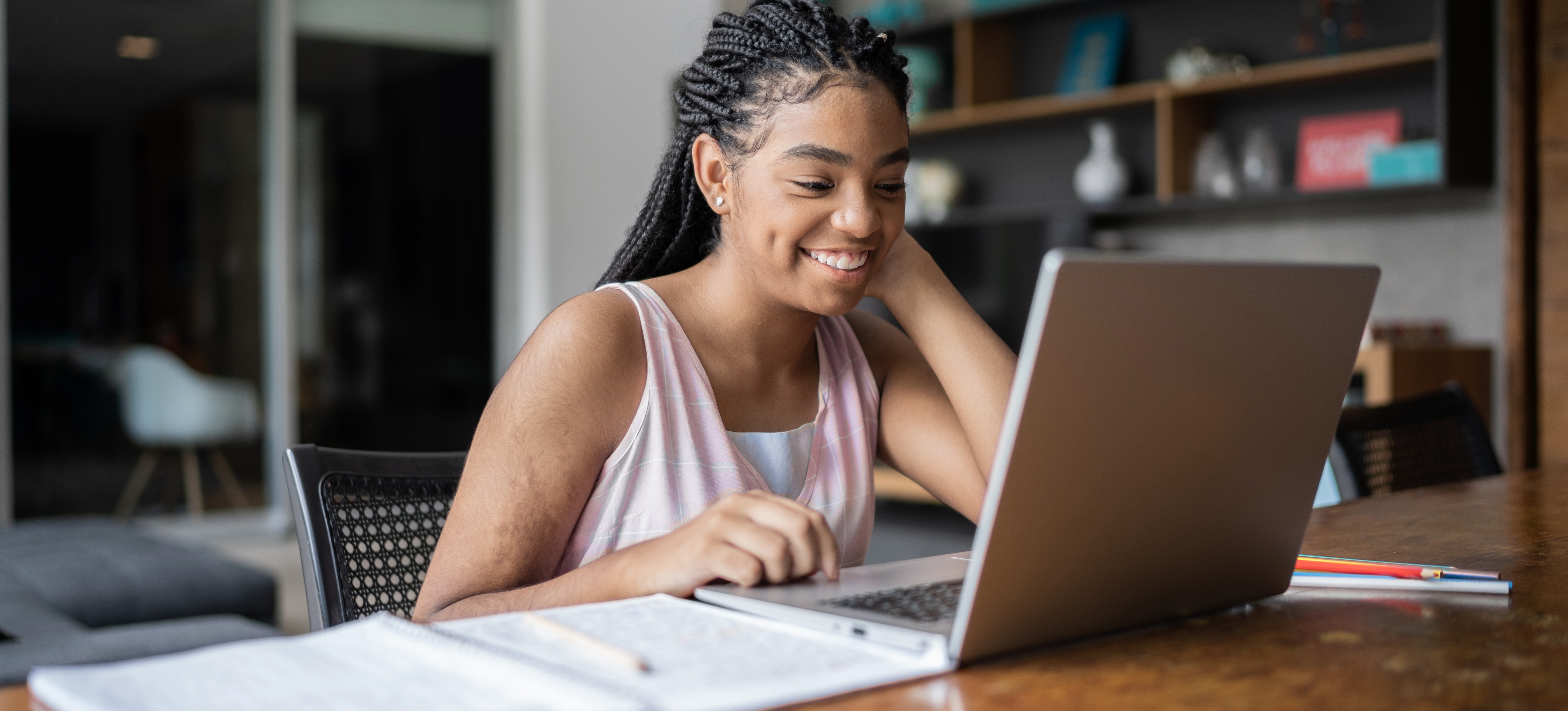 [Featured Image] A learner studying an online course at home, smiling while looking at their laptop screen.
