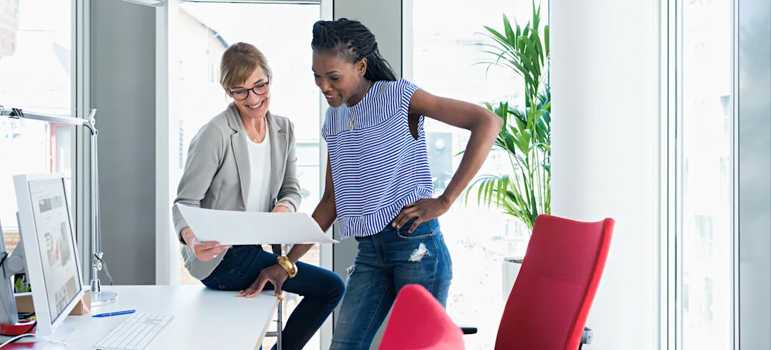 [Featured Image] Two machine learning professionals look over some paperwork in an office and talk about diffusion models.
