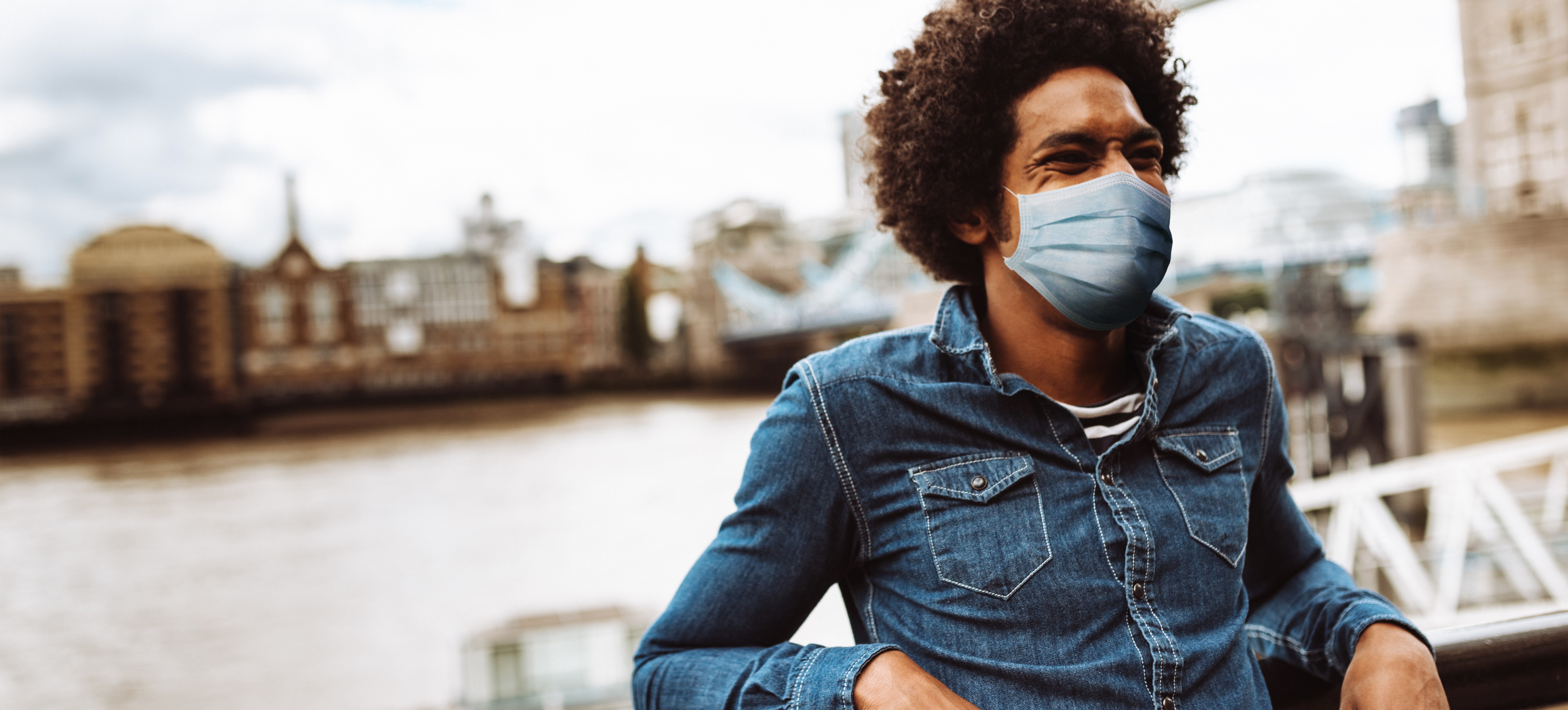 [Featured Image] A tourist wears a mask after researching social epidemiology and the potential spread of a health condition affecting the local population. 

