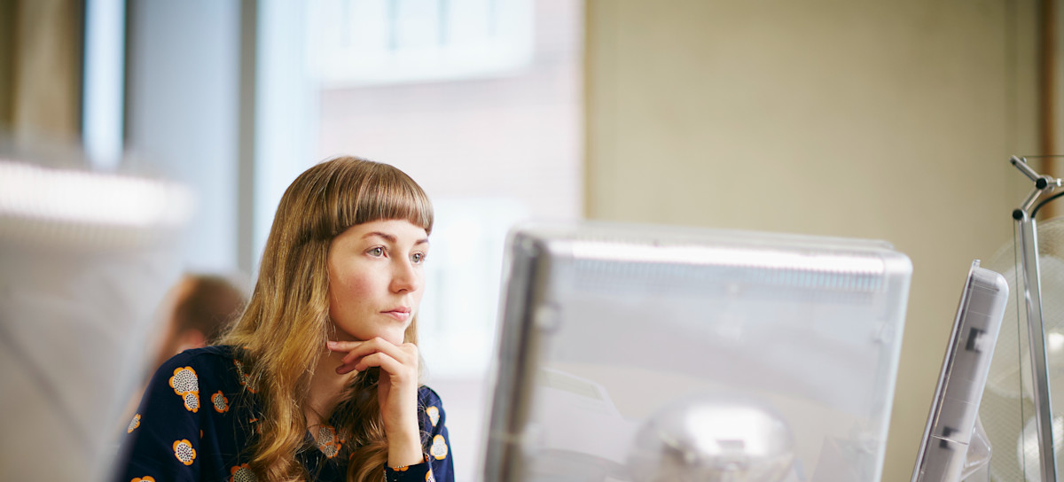 [Featured image] A cloud architect, wearing a blue patterned dress, working in front of their desktop.
