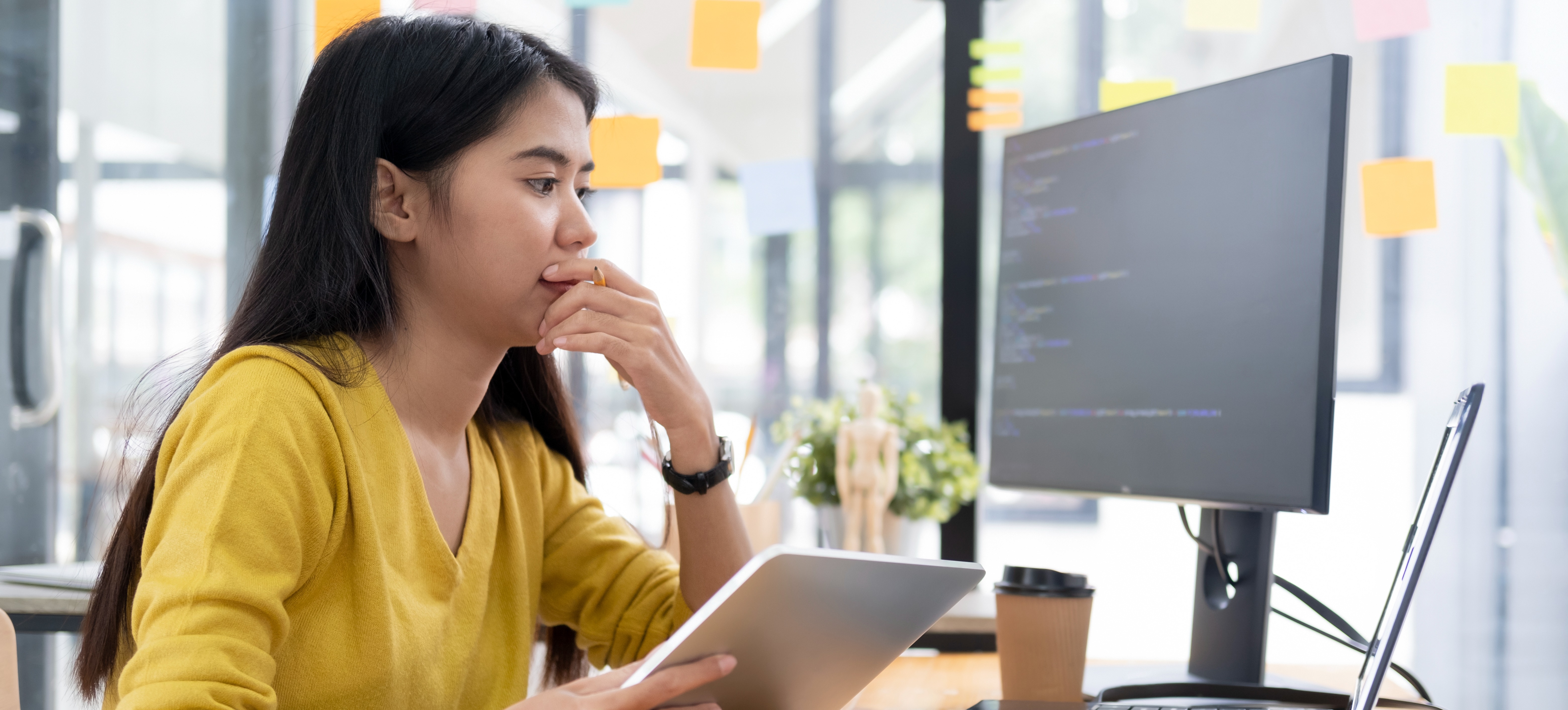 [Featured image]: A person sitting in front of a computer takes notes to decide which programming language they should learn for app development.