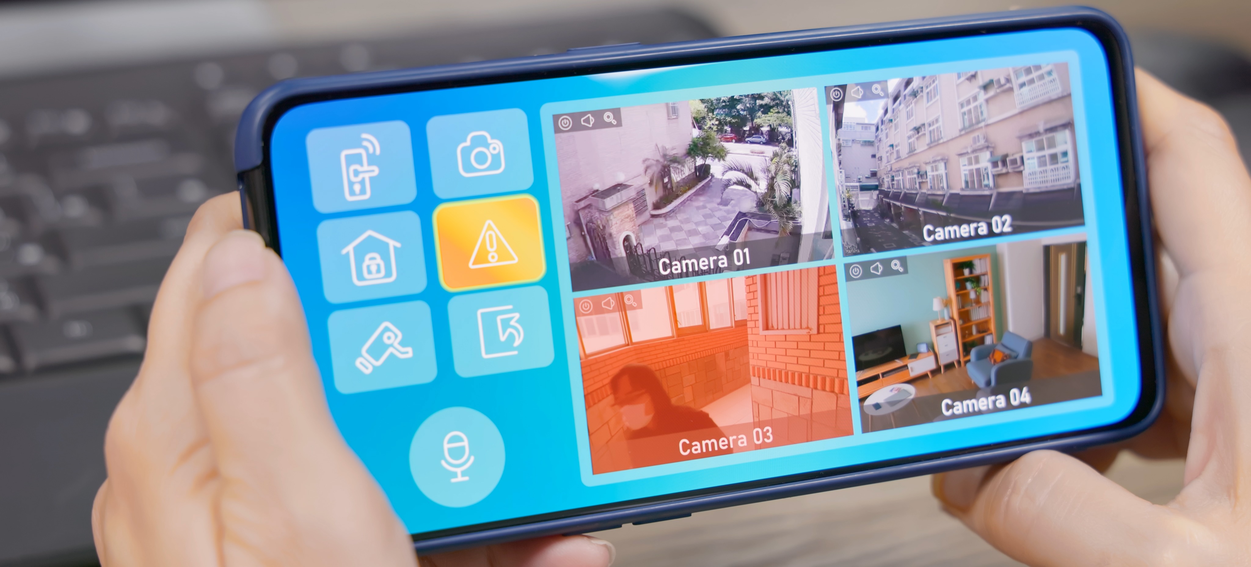 [Featured image] A person is holding a smart device displaying four security cameras activated by ambient intelligence.

