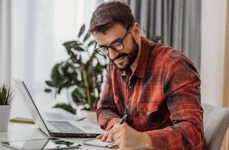 [Featured Image] A cybersecurity professional sits at a desk and works to prevent IoT attacks. 