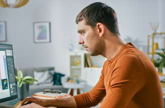 [Featured Image] A UX designer works on their laptop in an office to find the best information architecture for his company's mobile app. 