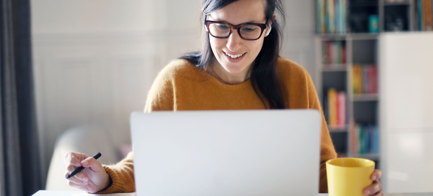 [Featured image] A person in an orange sweater sits at their laptop with a yellow mug and a notebook working on a certificate program.