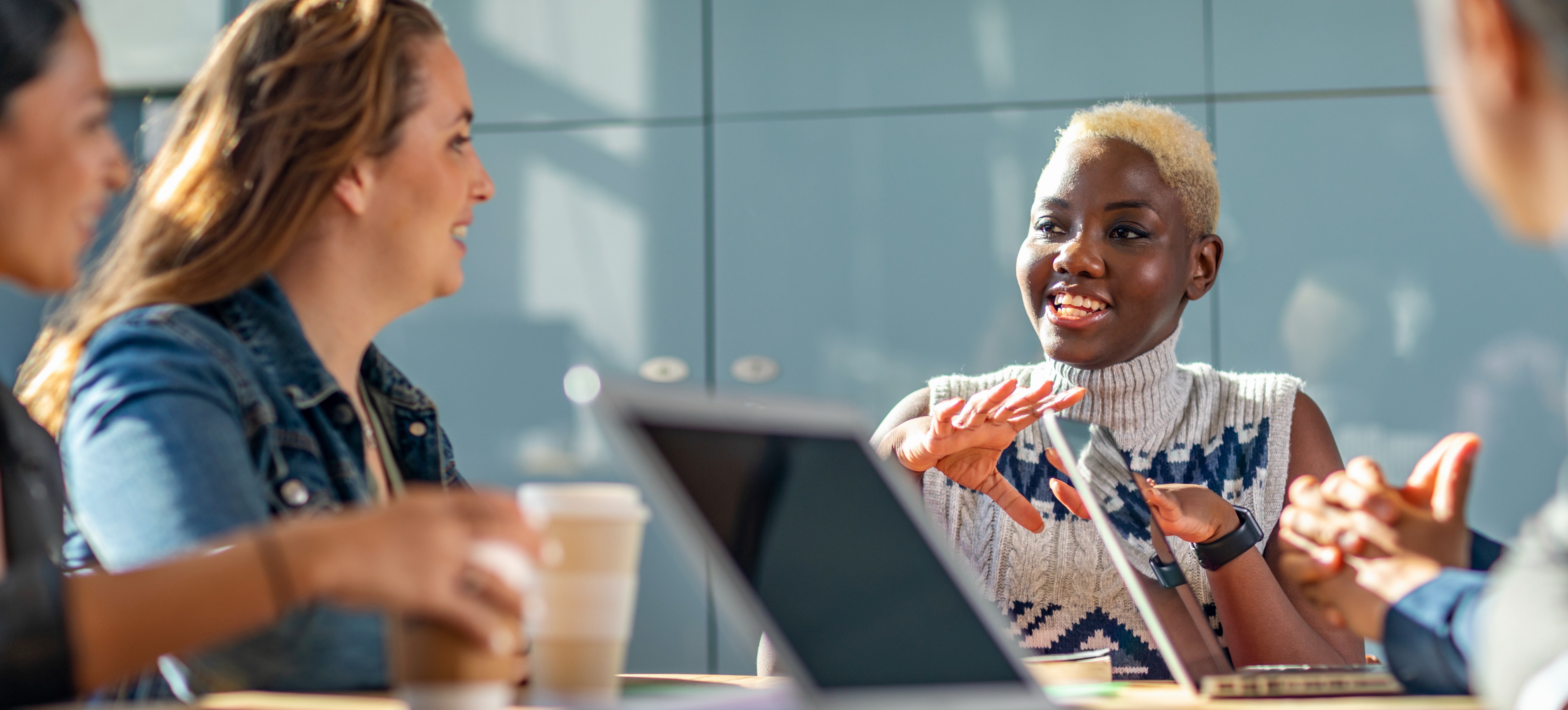 [Featured Image] A cheerful, smiling group of professionals sitting around a table and collaborating after discovering what classes are required for a business degree.