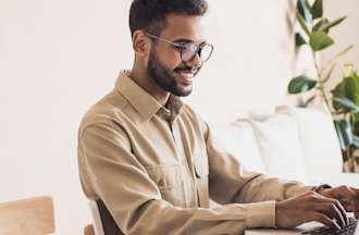 [Featured image] A man sits at home and uses his laptop to take an online course on Excel, in which he learns about the difference between formulas and functions. 

