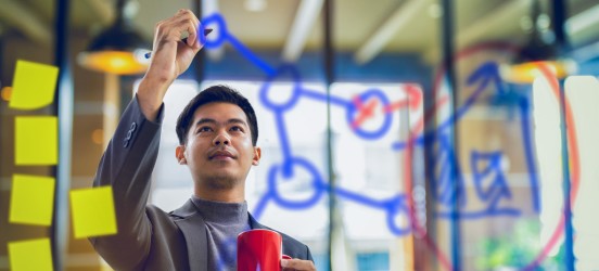 [Imagen destacada] Un desarrollador de la nube examina un diagrama de red en un tablero de plexiglás