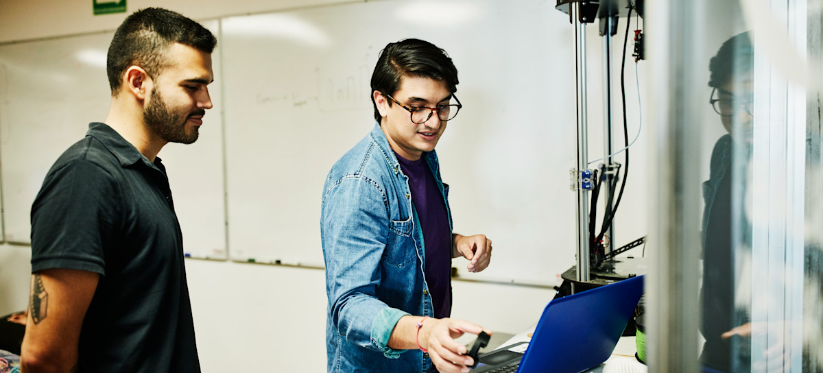 [Featured Image] Network engineers reviewing infrastructure diagrams on a laptop while discussing connectivity optimization solutions.
