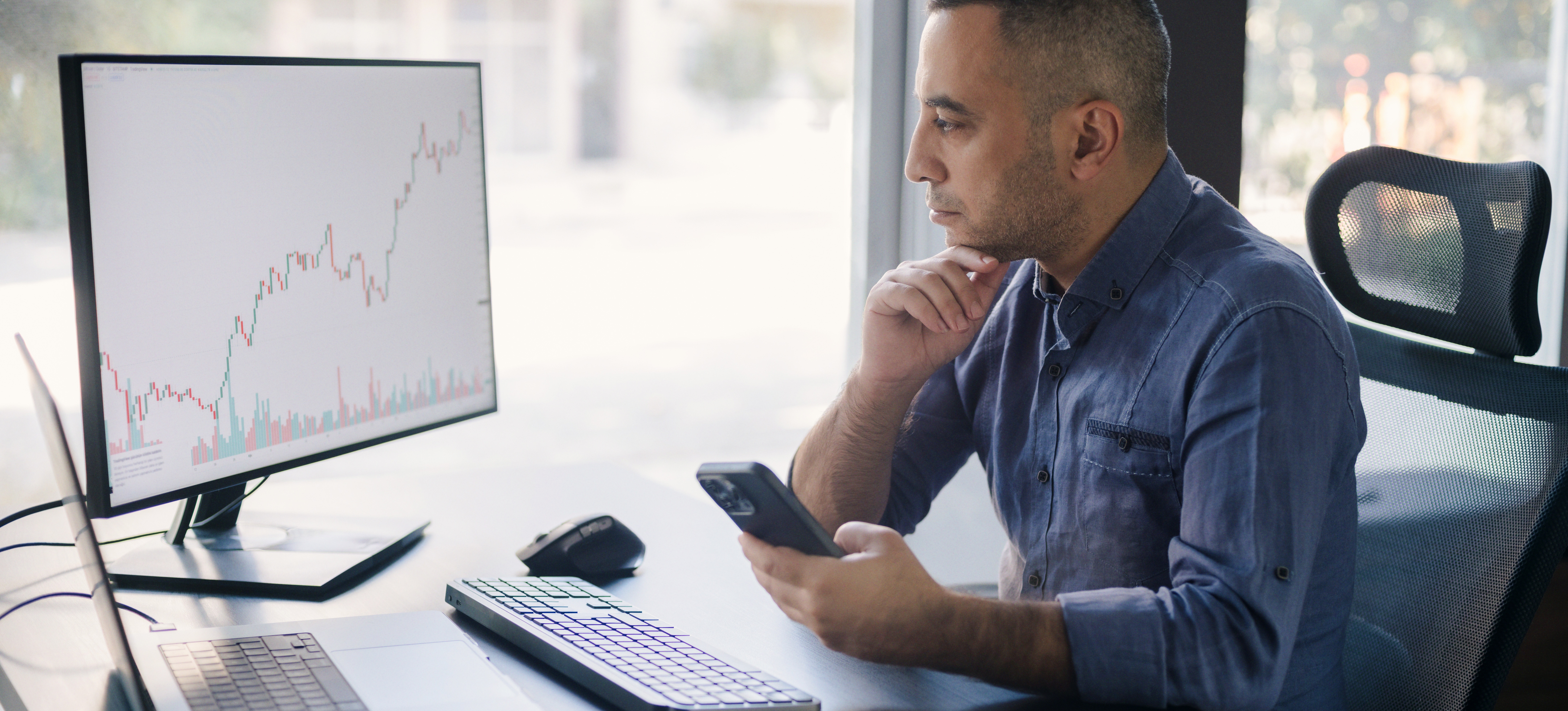 [Featured Image] A business person sits at their office desk assessing a chart on their computer monitor made with a Google Sheet slicer.
