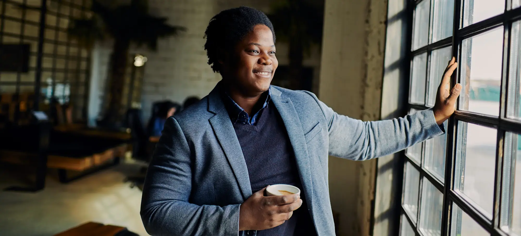 [Featured Image] Smiling person looks out the window as he contemplates how to quit his job.