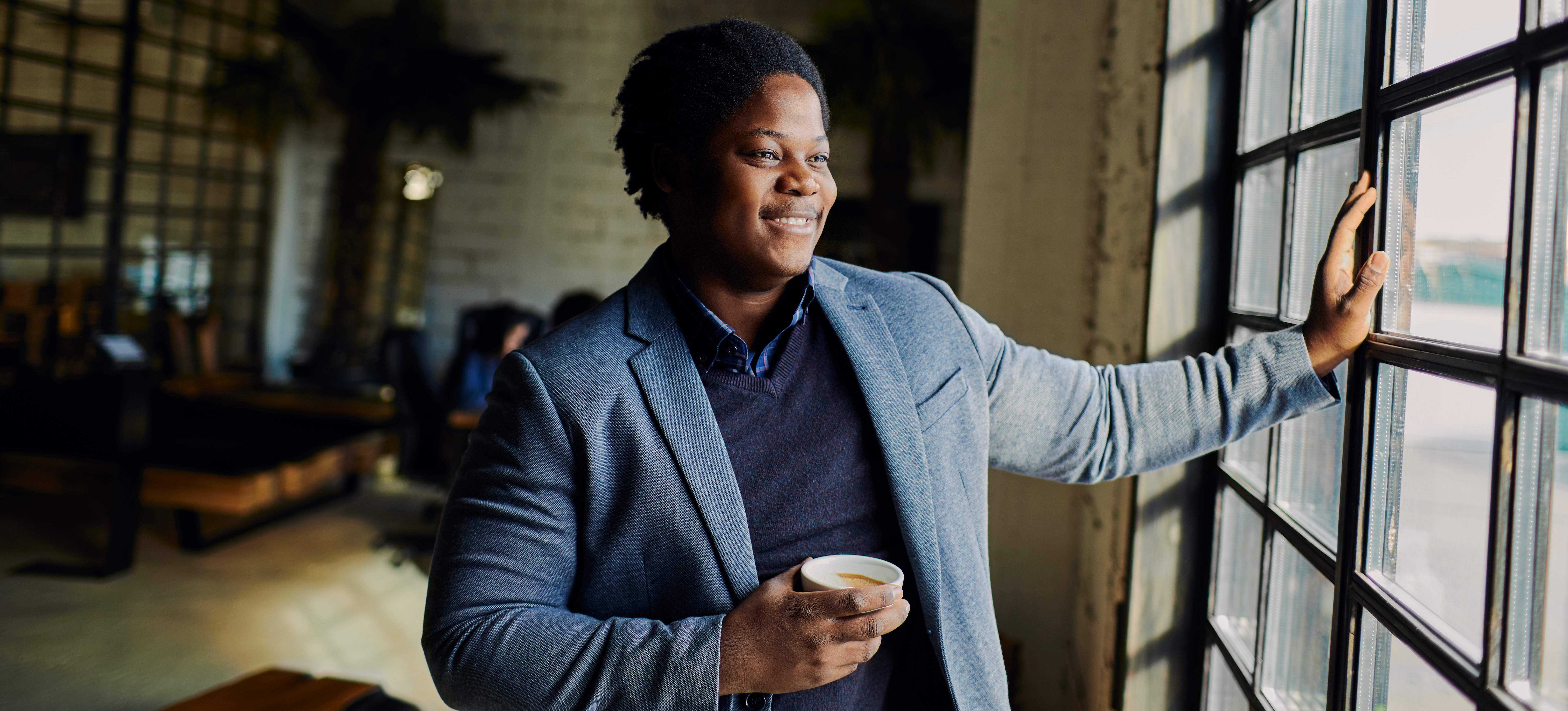 [Featured Image] Smiling person looks out the window as he contemplates how to quit his job.