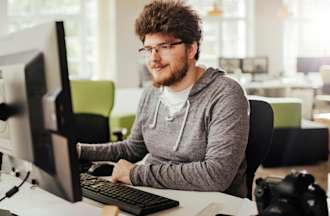 [Featured image] A person in a gray hoodie sits at their desk and launches BIOS on their desktop computer.