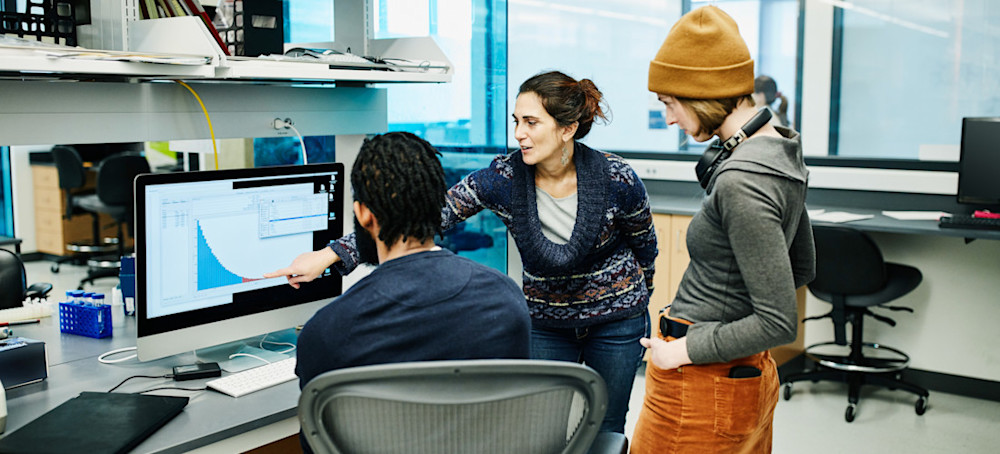 [Featured Image] Three data analysts look at a graph on a computer screen created using exploratory analysis.
