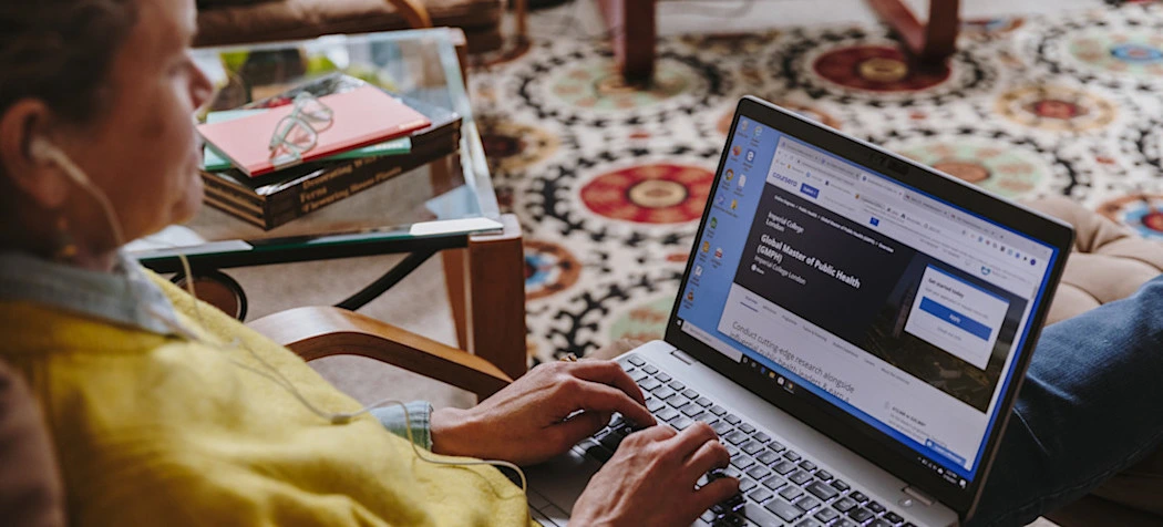 [Featured Image] An SEO consultant wearing a yellow jacket is sitting at their desk researching marketing strategies. 