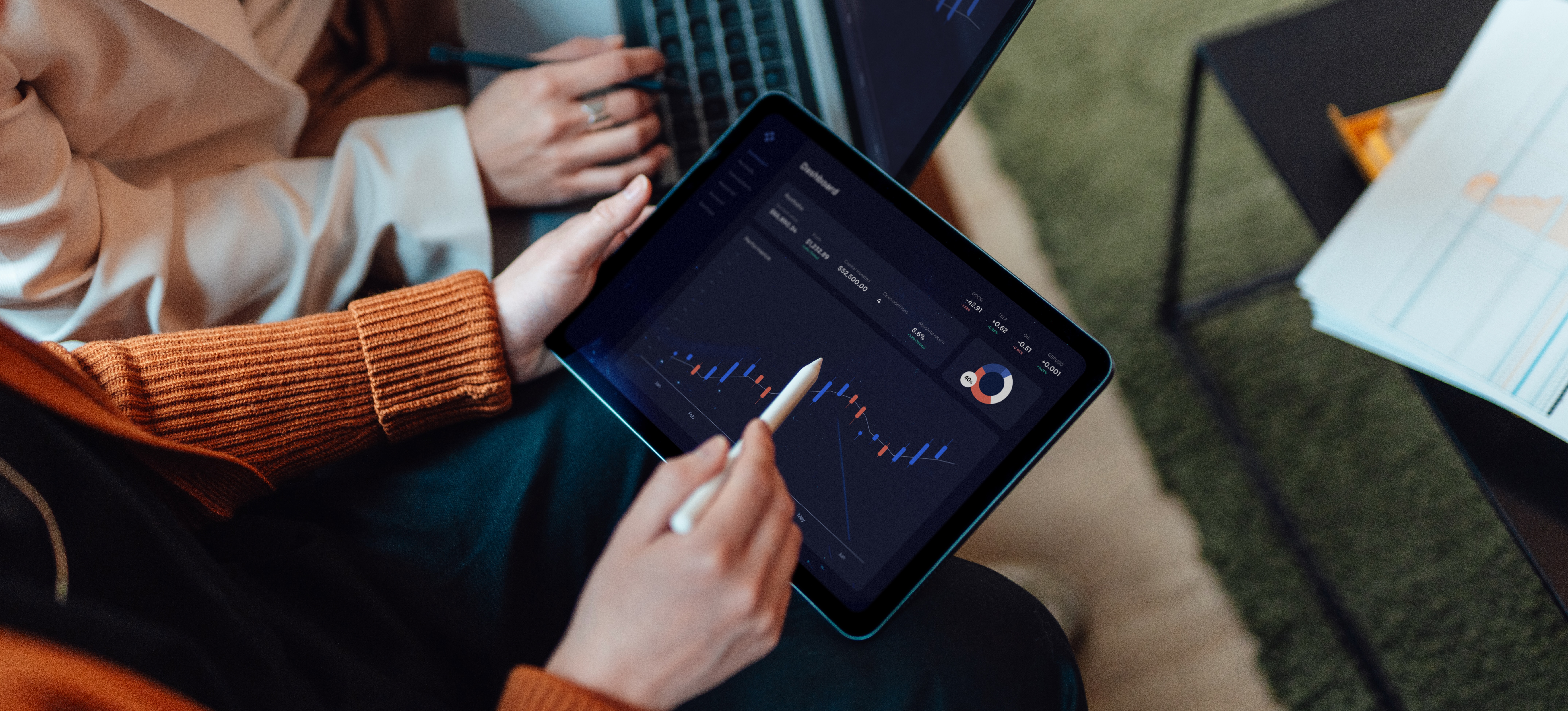 [Featured Images] Two business professionals look at a laptop and tablet and discuss data plotted with linear regression.