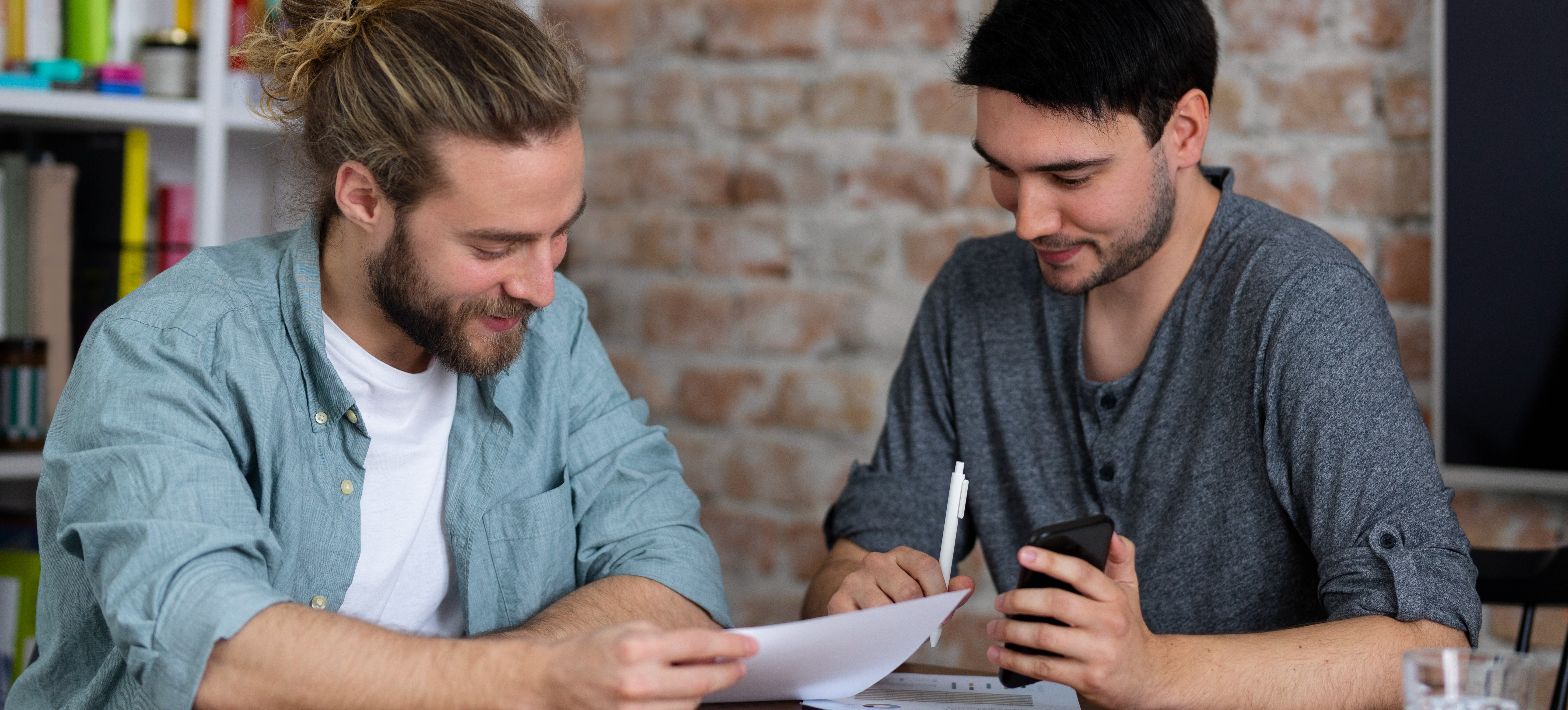 [Featured Image] Two college students look over student records to determine if a high GRE can compensate for their low GPA