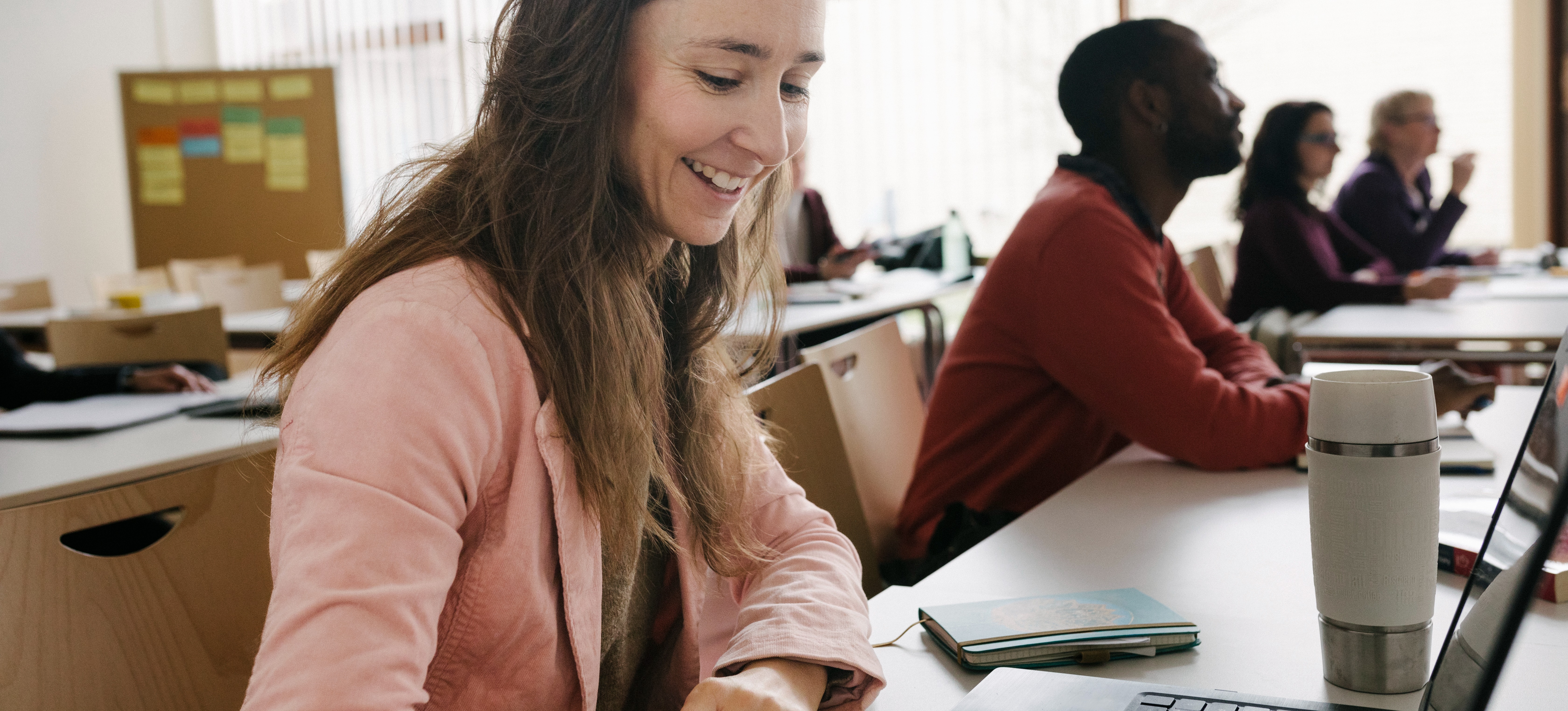 [Featured Image] A classroom of learners is smiling after learning about two-year degree jobs that are in demand. 