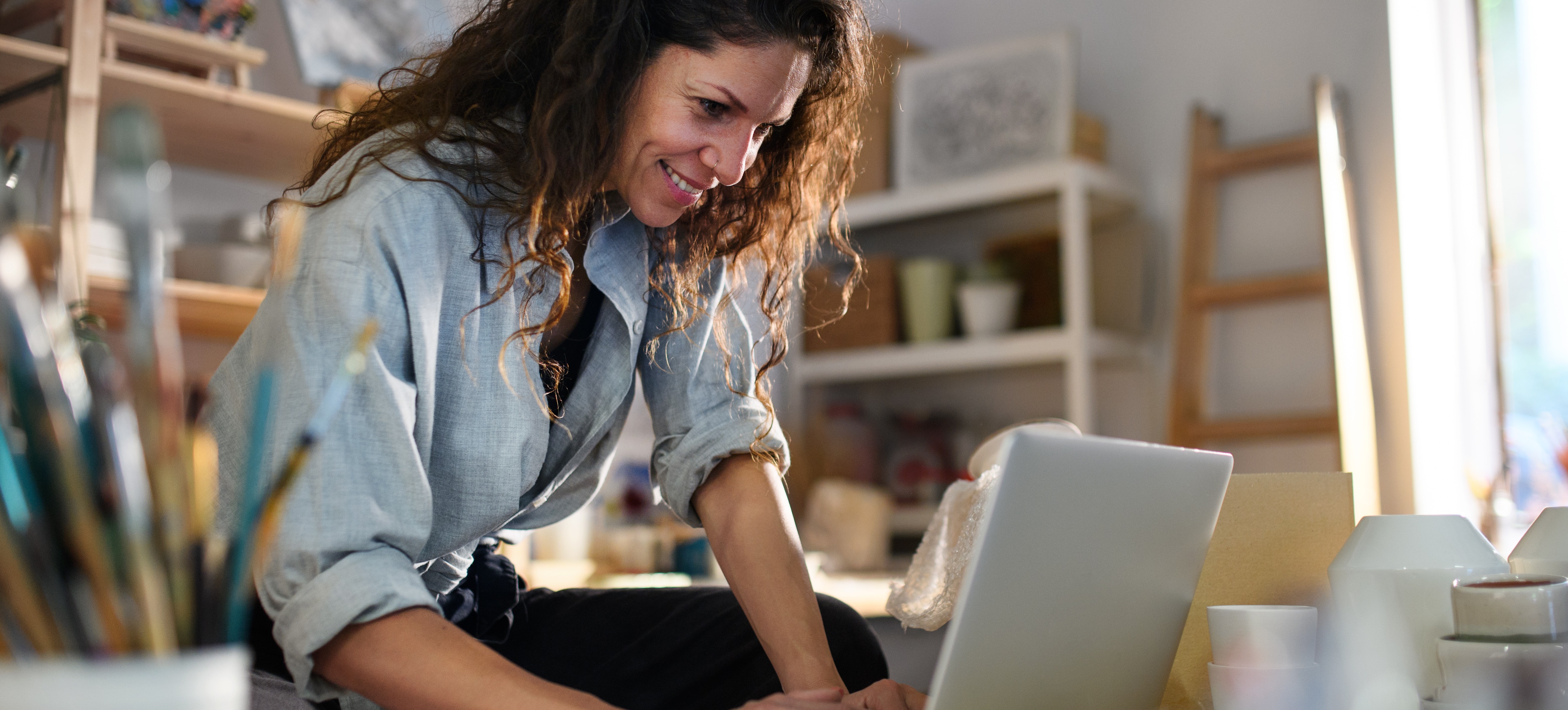 [Featured Image] A female small business owner sits at her desk with her laptop and looks at her marketing analytics.
