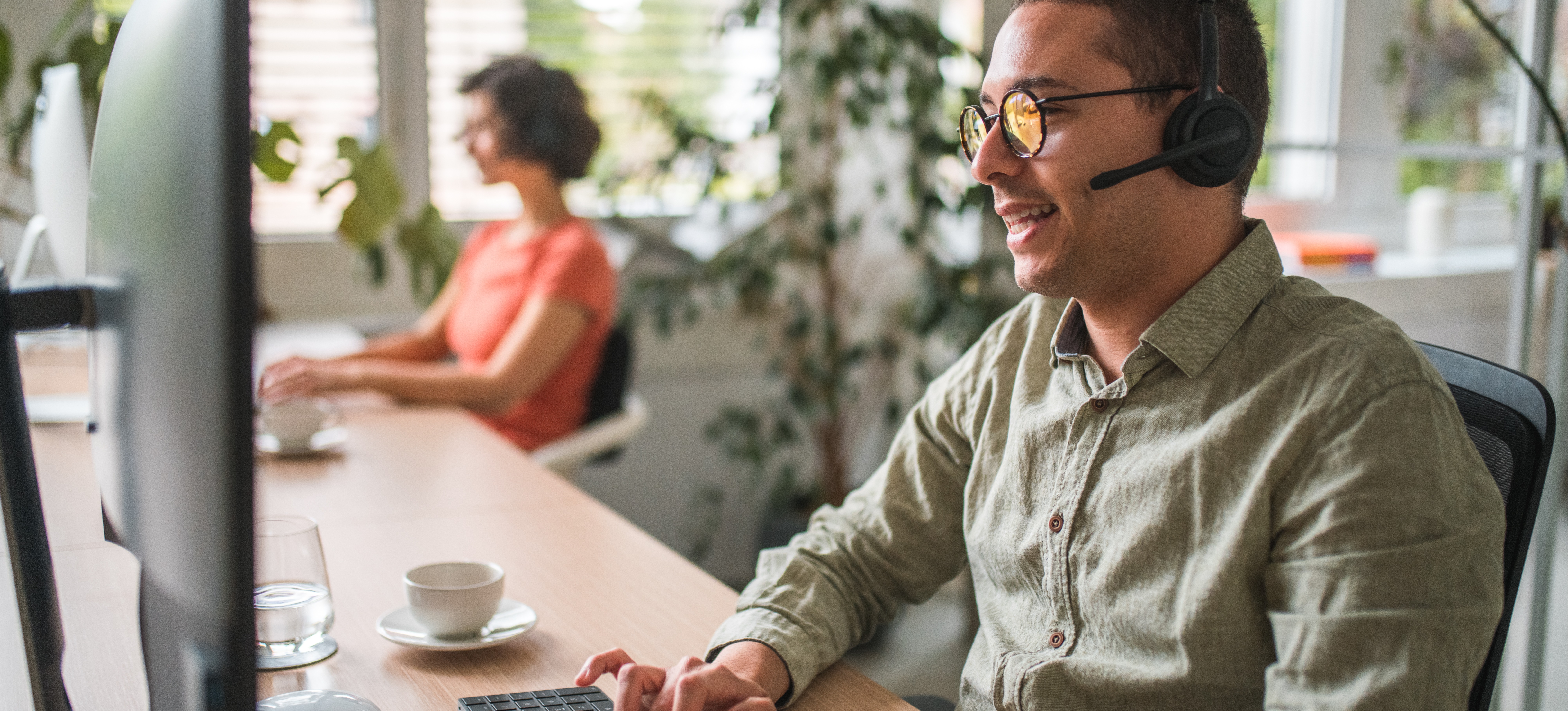 [Featured Image] A man wearing a headset and typing on a computer works in emergency communications, one of the many important CISA jobs. 
